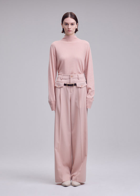 A model wears the ISSEY MIYAKE LUSTROUS WOOL PANTS trousers.