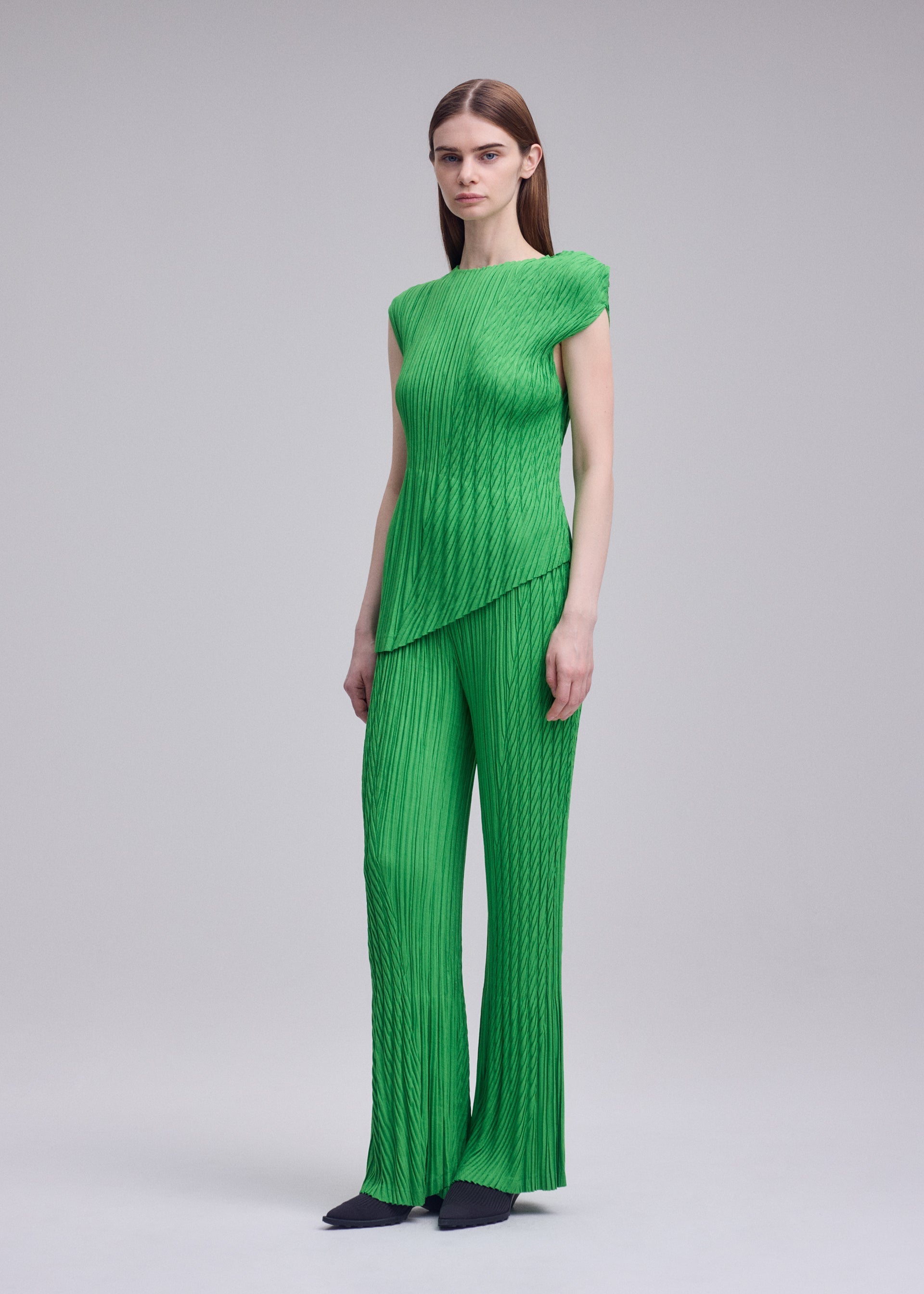 A model wears the ISSEY MIYAKE UNFURLING PLEATS unfurling-pleats-trousers-green-1.