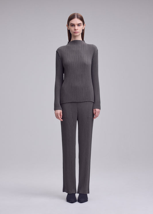 A model wears the ISSEY MIYAKE HATCHING PLEATS trousers.