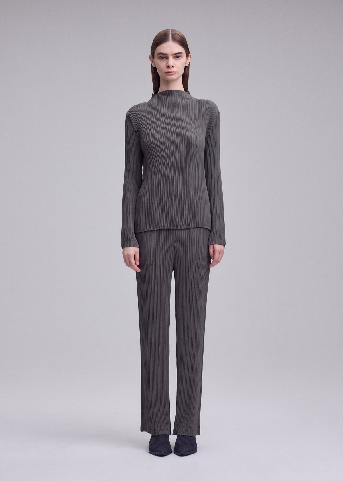 A model wears the ISSEY MIYAKE HATCHING PLEATS trousers.