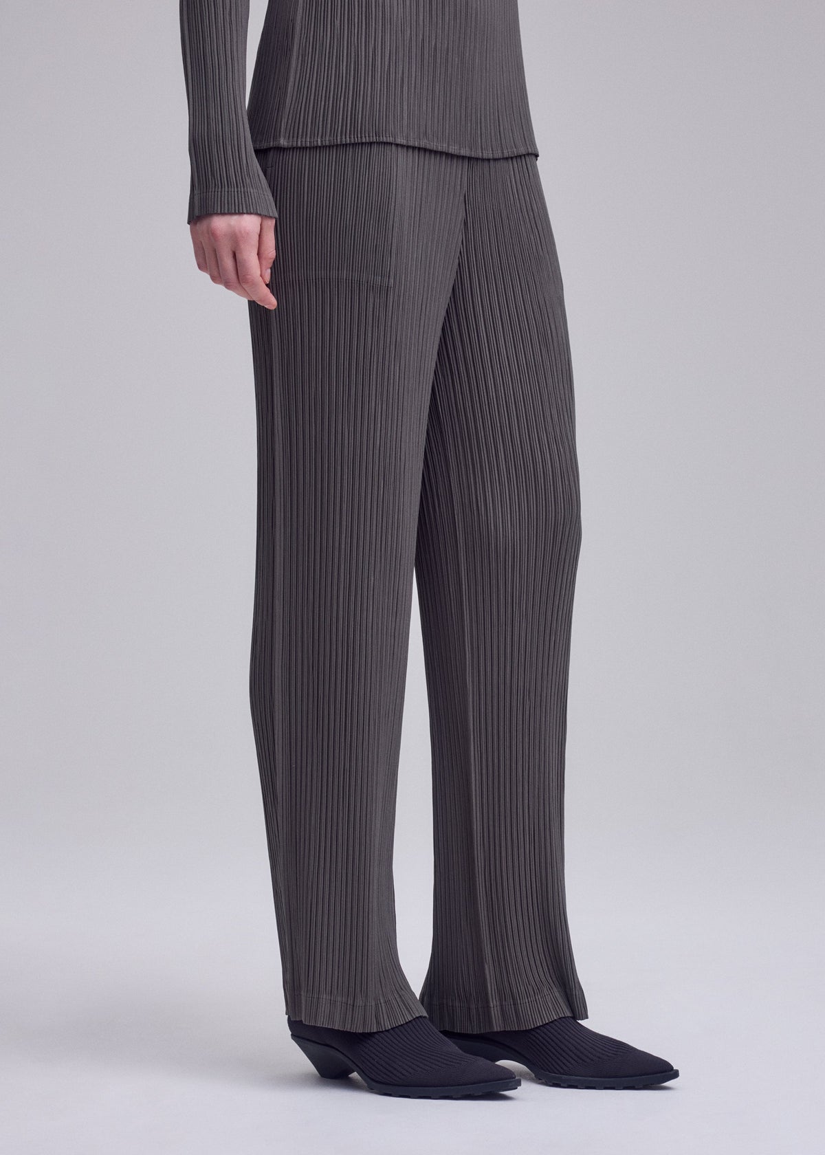 A model wears the ISSEY MIYAKE HATCHING PLEATS trousers.