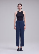 A model wears the ISSEY MIYAKE HATCHING BOTTOMS hatching-bottoms-trousers-dark-navy.