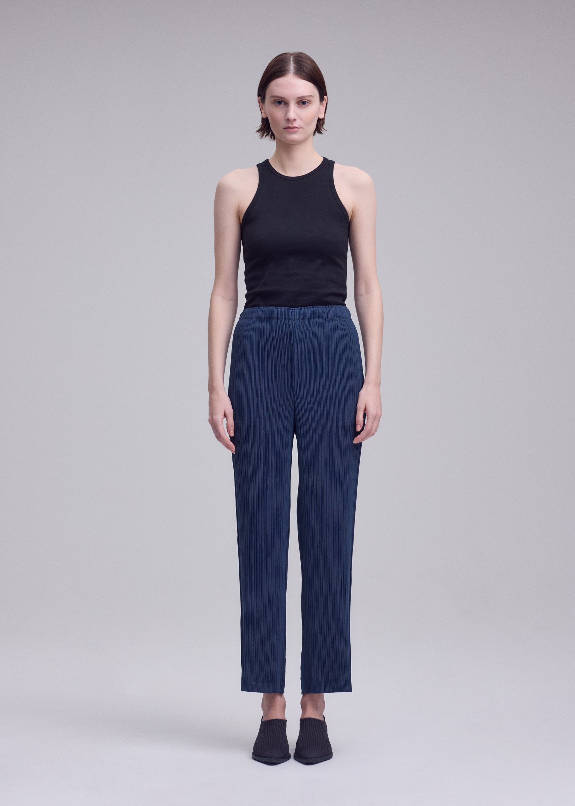 A model wears the ISSEY MIYAKE HATCHING BOTTOMS hatching-bottoms-trousers-dark-navy.