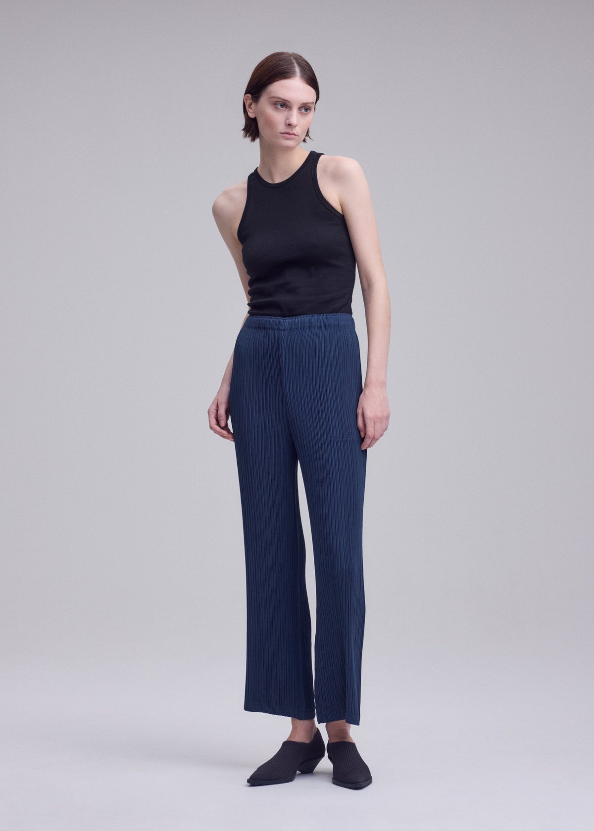 A model wears the ISSEY MIYAKE HATCHING BOTTOMS hatching-bottoms-trousers-dark-navy.