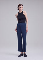 A model wears the ISSEY MIYAKE HATCHING BOTTOMS hatching-bottoms-trousers-dark-navy.