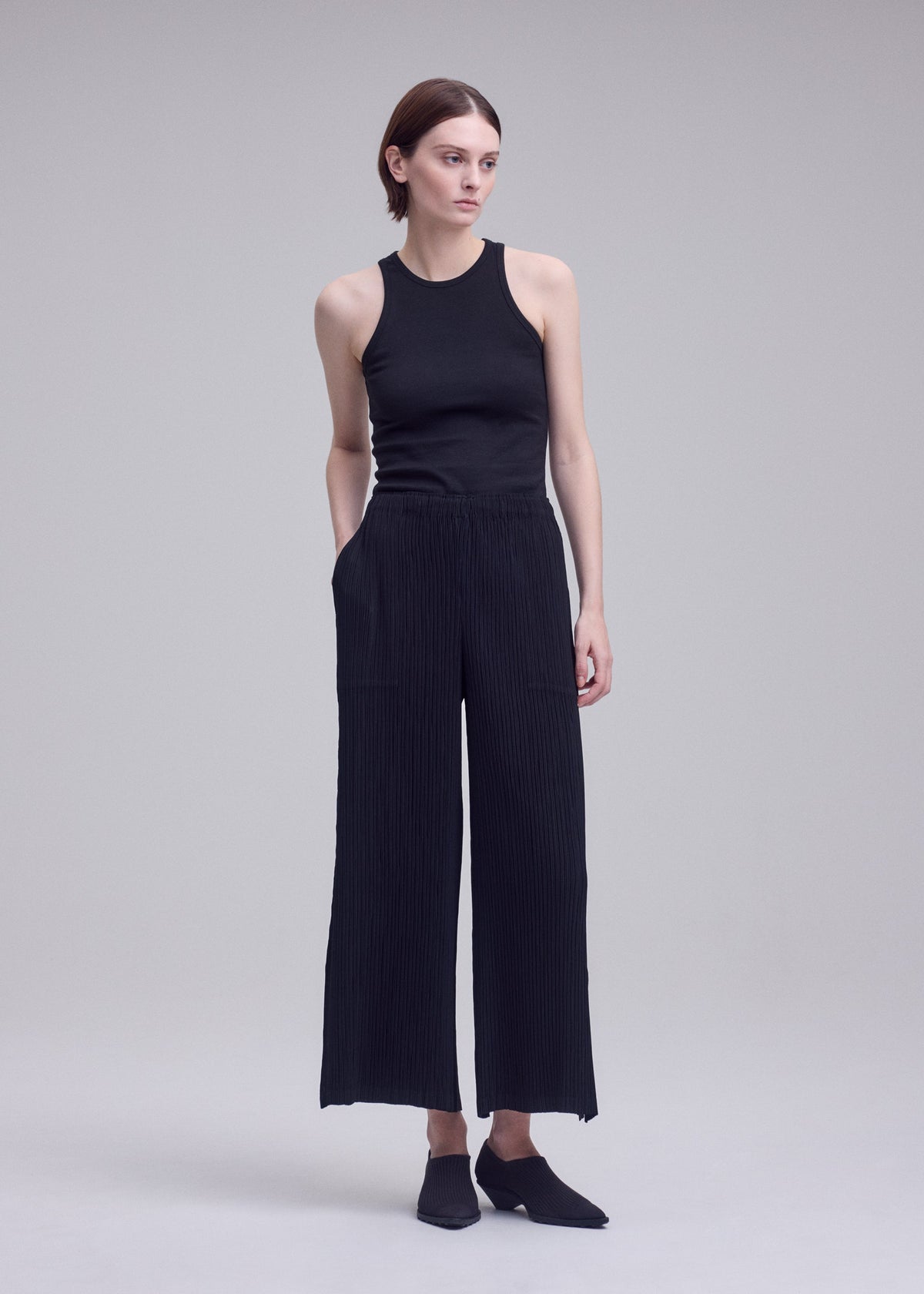 A model wears the ISSEY MIYAKE HATCHING BOTTOMS hatching-bottoms-trousers-dark-navy-1.