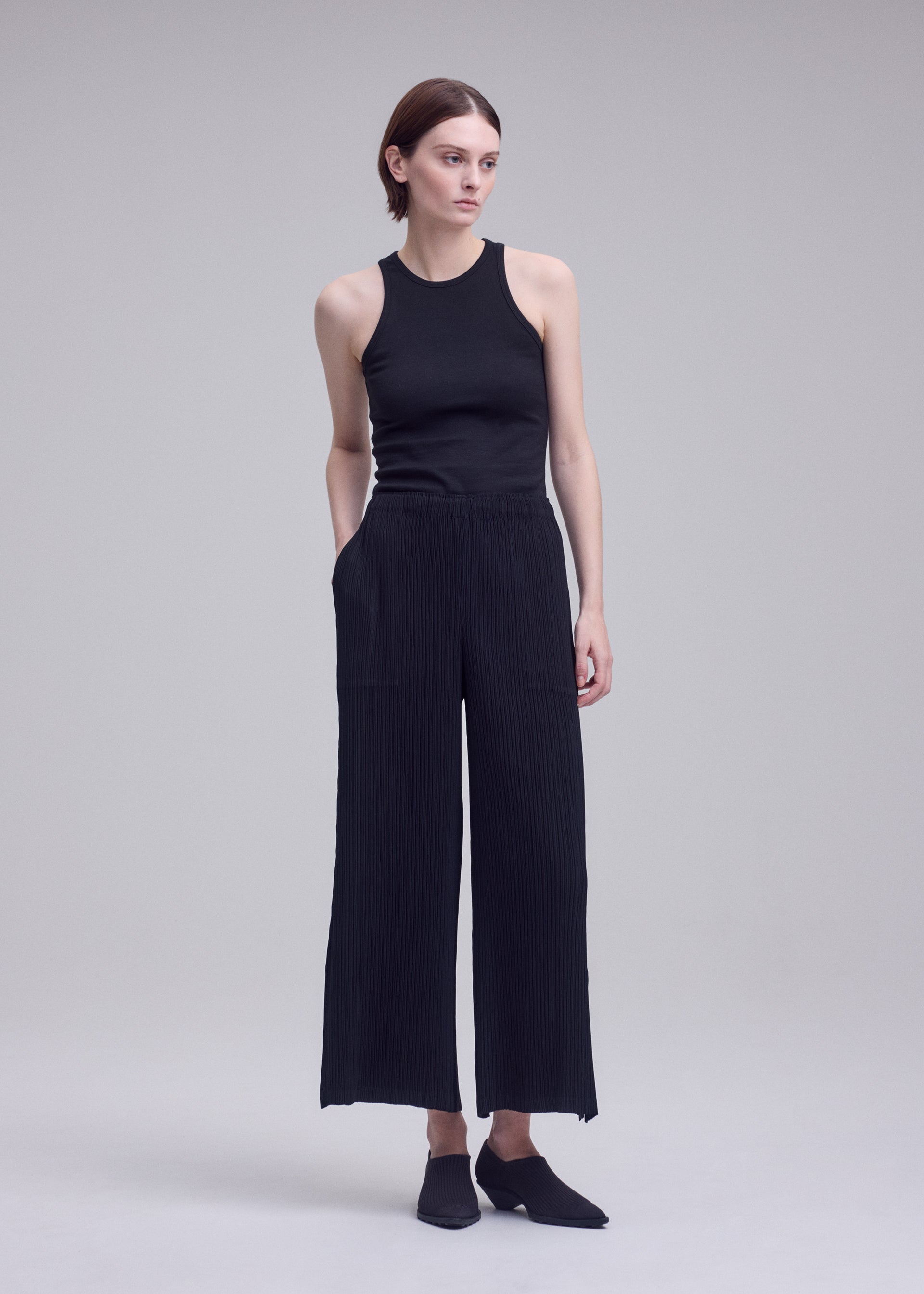 A model wears the ISSEY MIYAKE HATCHING BOTTOMS hatching-bottoms-trousers-dark-navy-1.