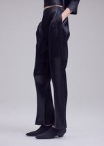 A model wears the ISSEY MIYAKE GLOSSED PANELS PLEATS trousers.