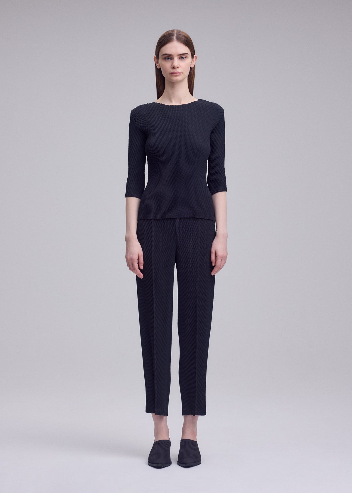 A model wears the ISSEY MIYAKE RHOMBUS PLEATS rhombus-pleats-trousers-dark-green-1.
