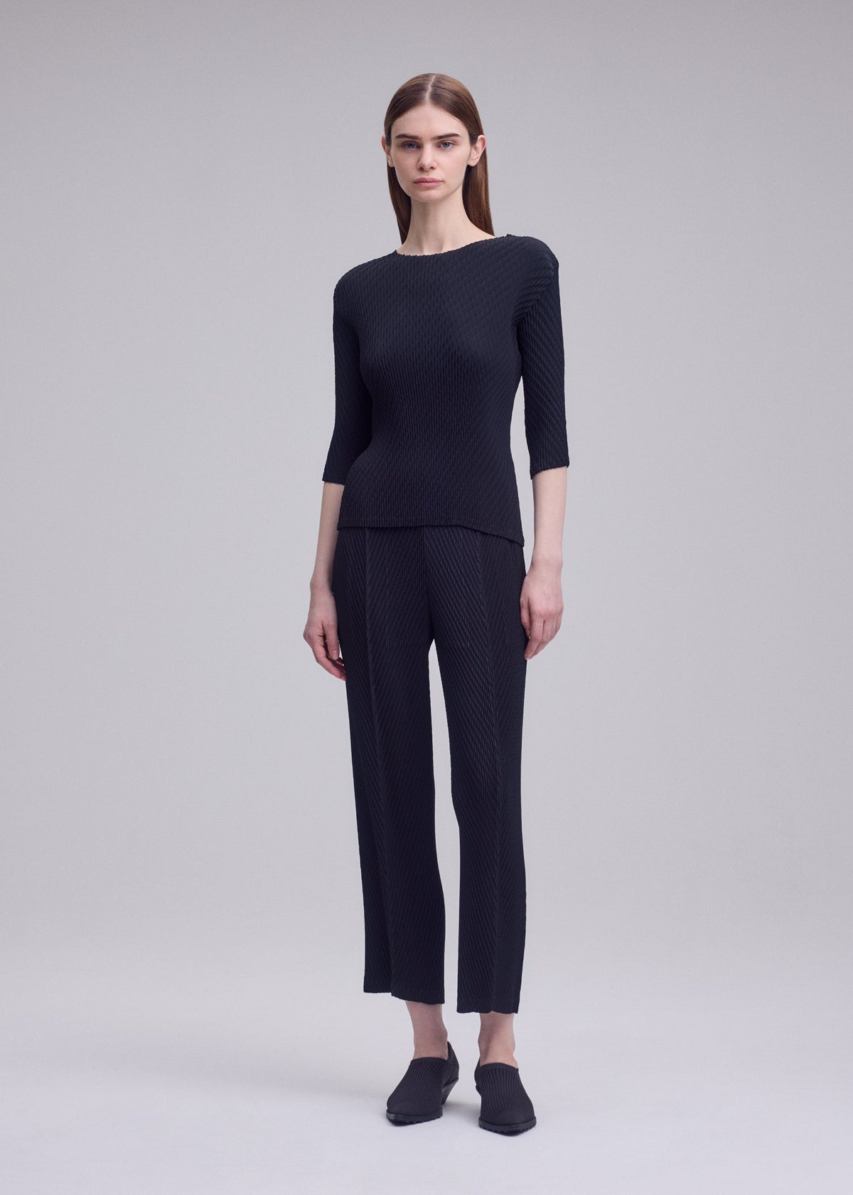 A model wears the ISSEY MIYAKE RHOMBUS PLEATS rhombus-pleats-trousers-dark-green-1.