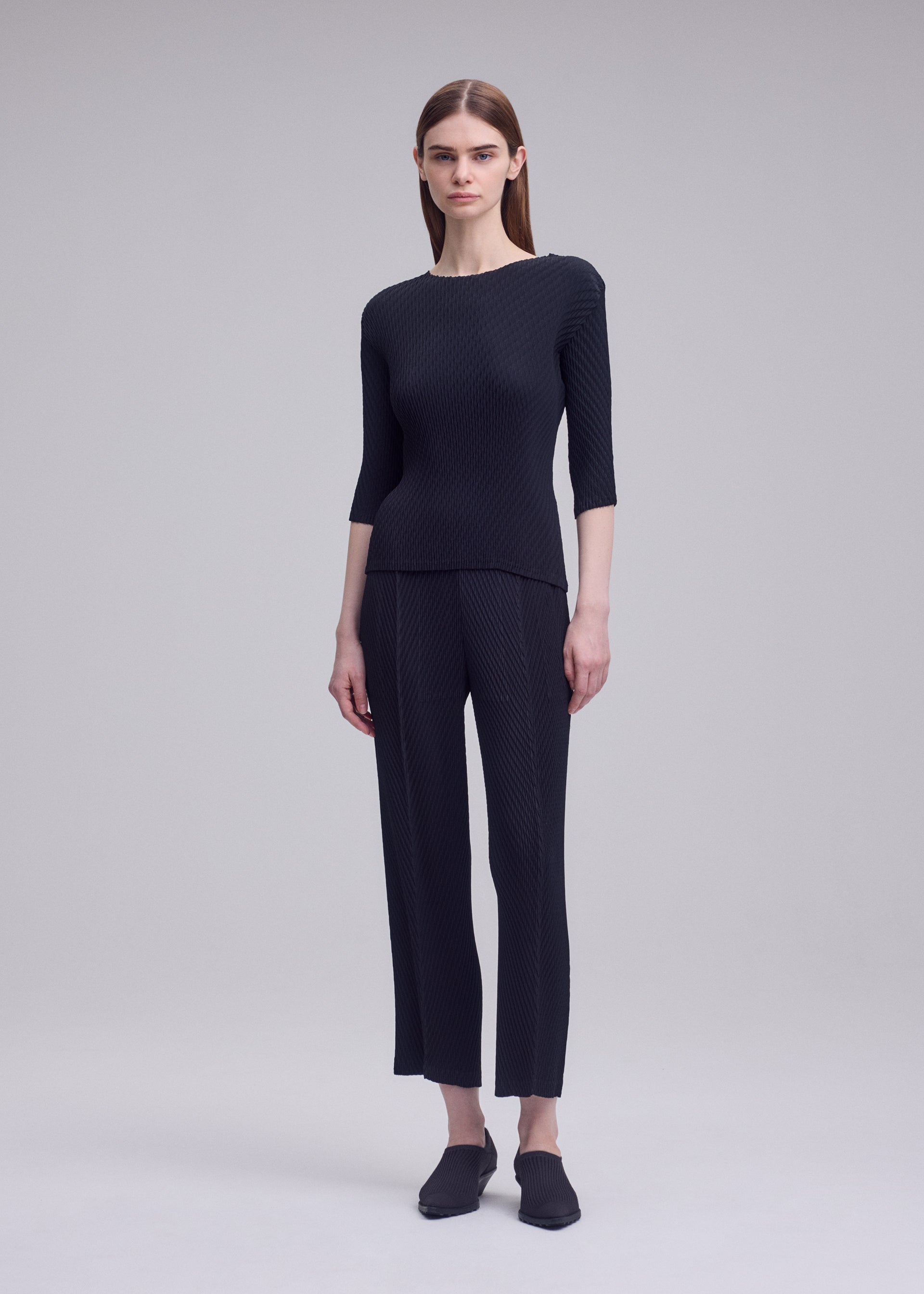 A model wears the ISSEY MIYAKE RHOMBUS PLEATS rhombus-pleats-trousers-dark-green-1.