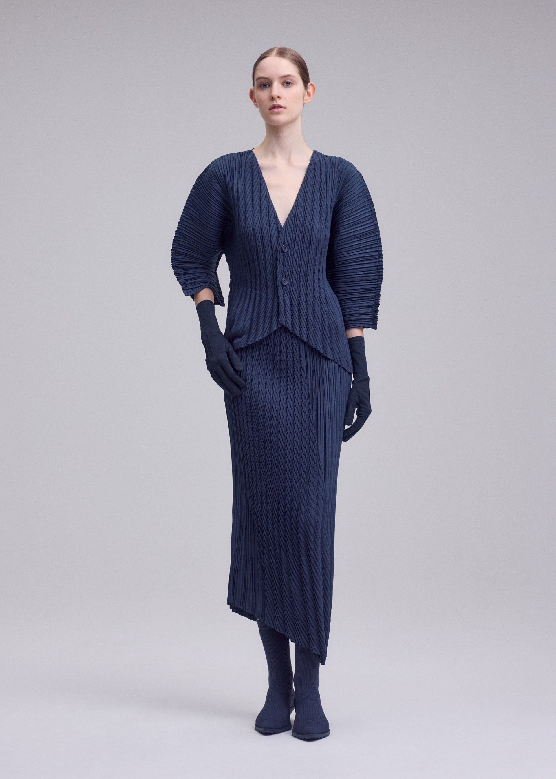A model wears the ISSEY MIYAKE UNFURLING PLEATS unfurling-pleats-skirt-off-white.