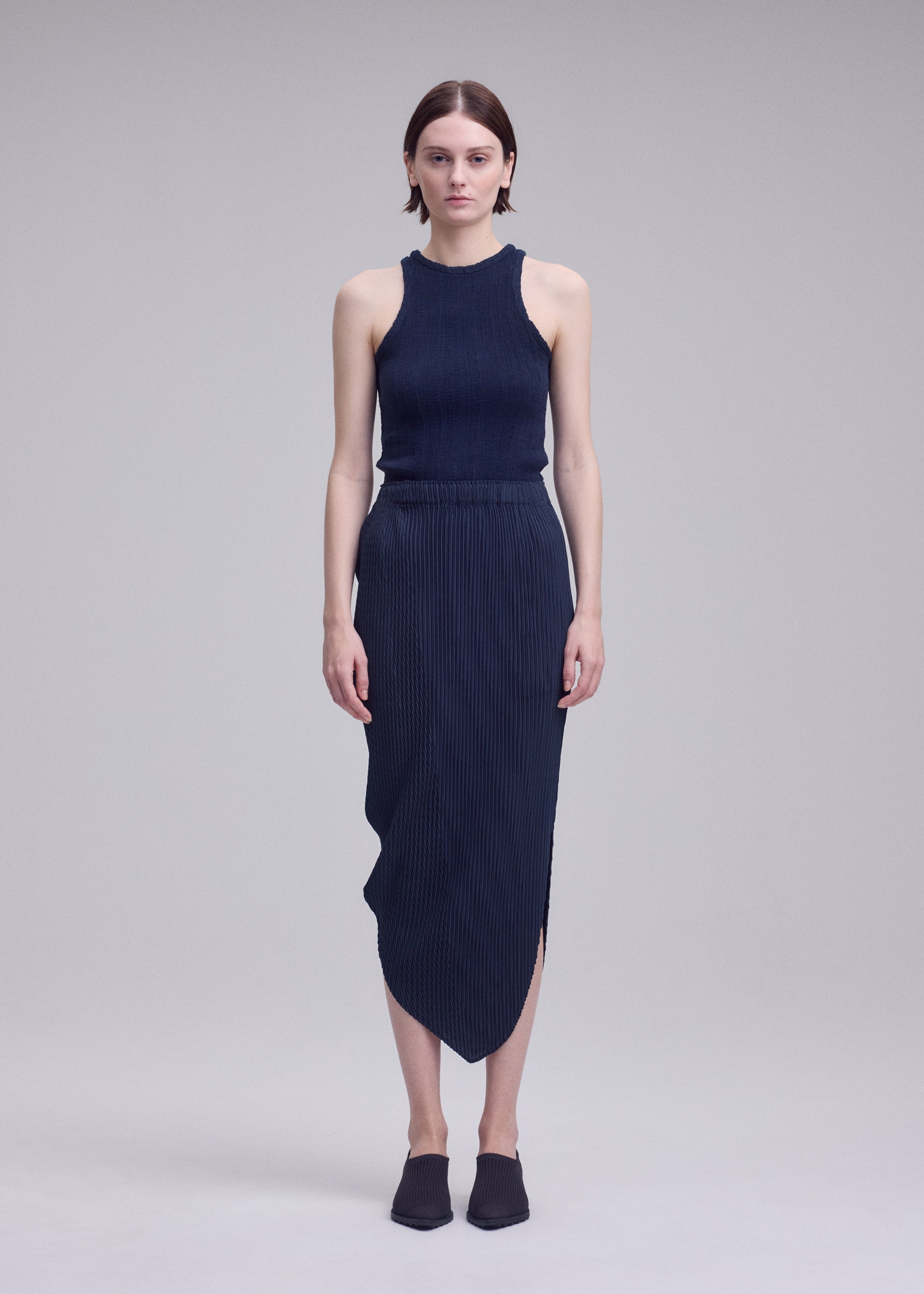 A model wears the ISSEY MIYAKE LEAF PLEATS leaf-pleats-skirt-dark-navy.