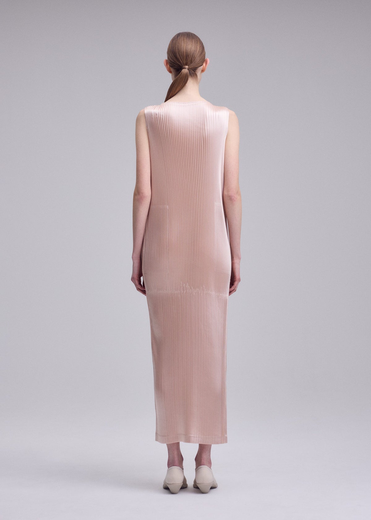 A model wears the ISSEY MIYAKE GLOSSED PANELS PLEATS dress.