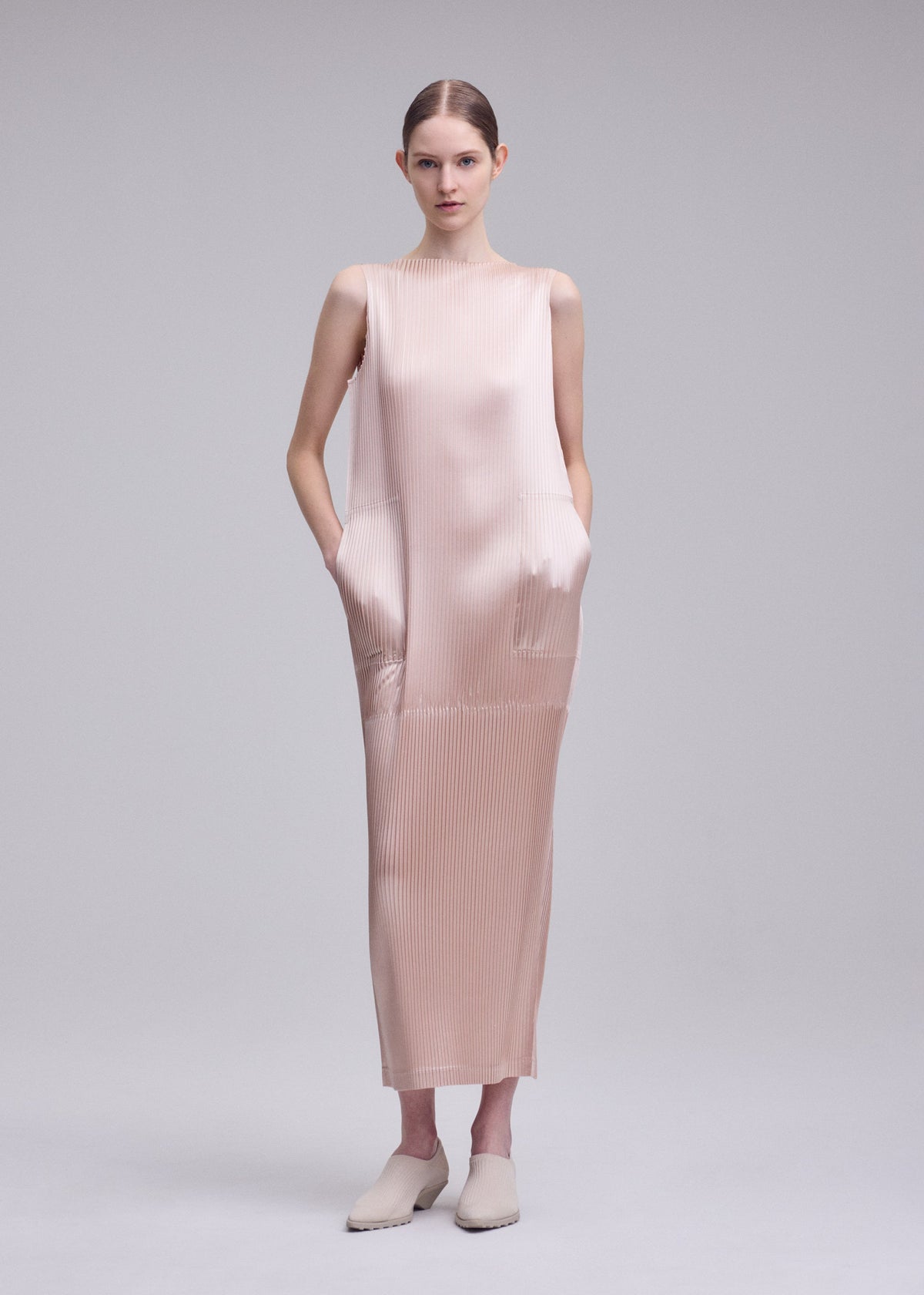 A model wears the ISSEY MIYAKE GLOSSED PANELS PLEATS dress.
