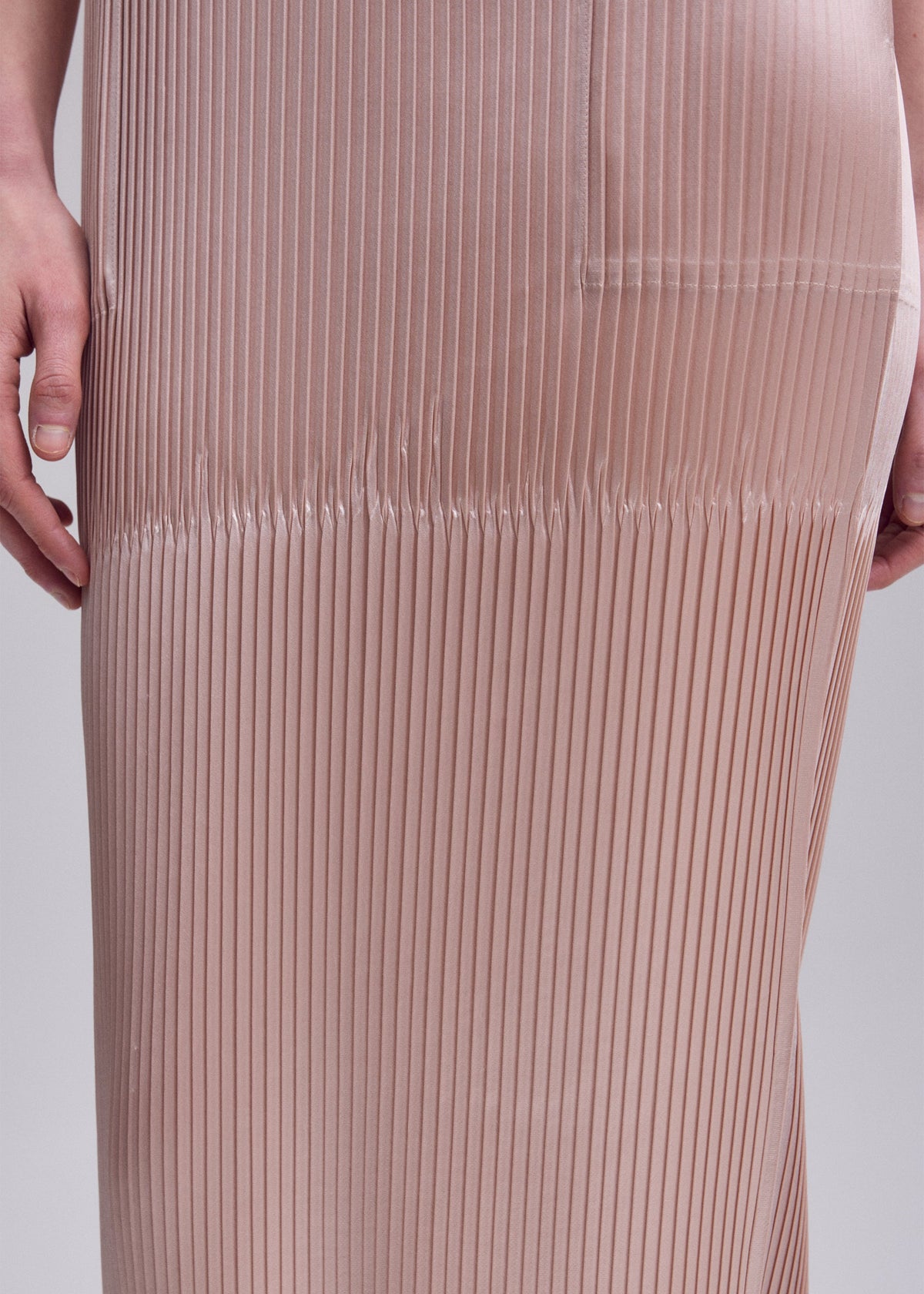 A model wears the ISSEY MIYAKE GLOSSED PANELS PLEATS dress.
