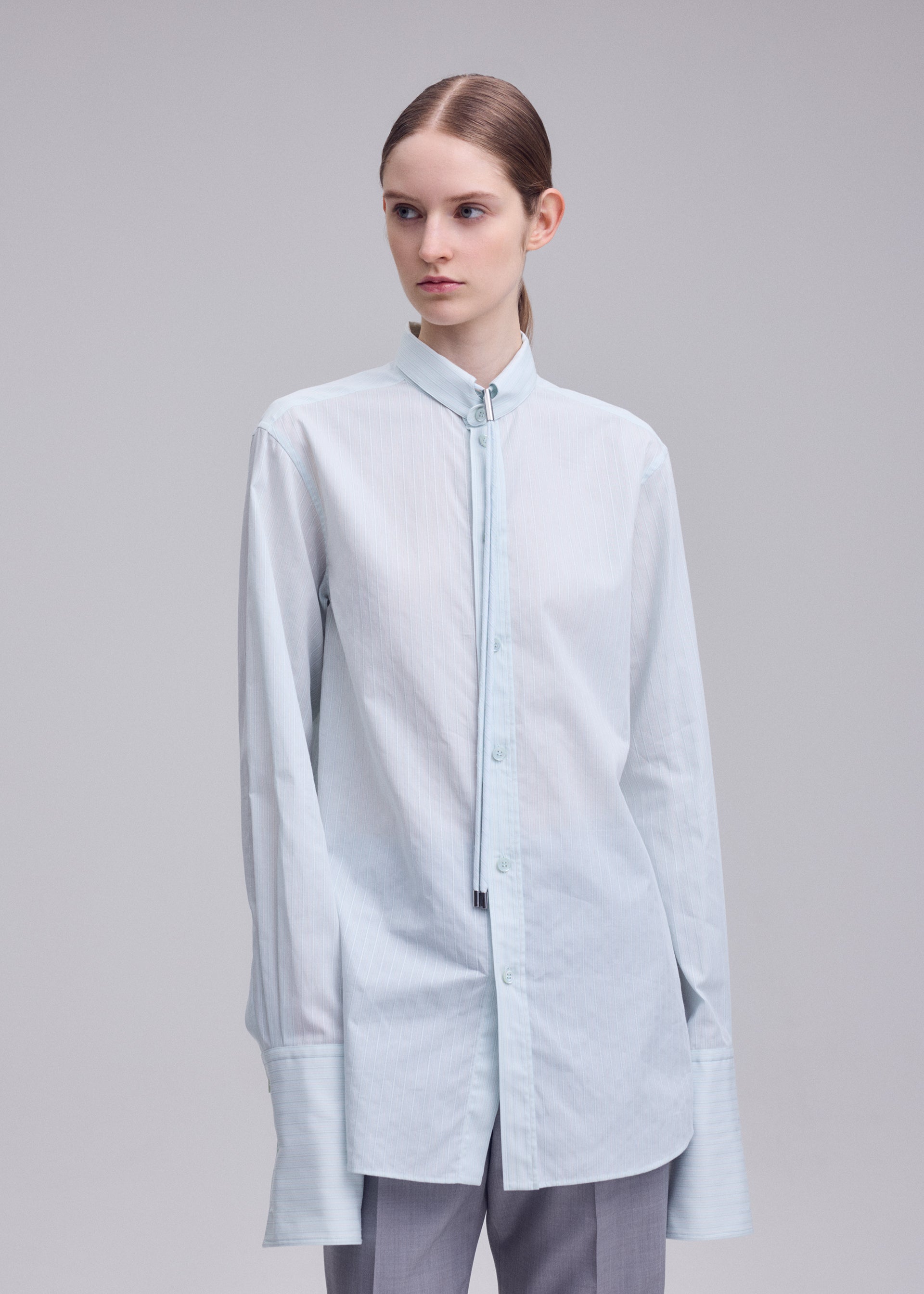 A model wears the ISSEY MIYAKE MONSIEUR SHIRT(DOBBY STRIPE) monsieur-shirt-dobby-stripe-shirt-blue-hued.
