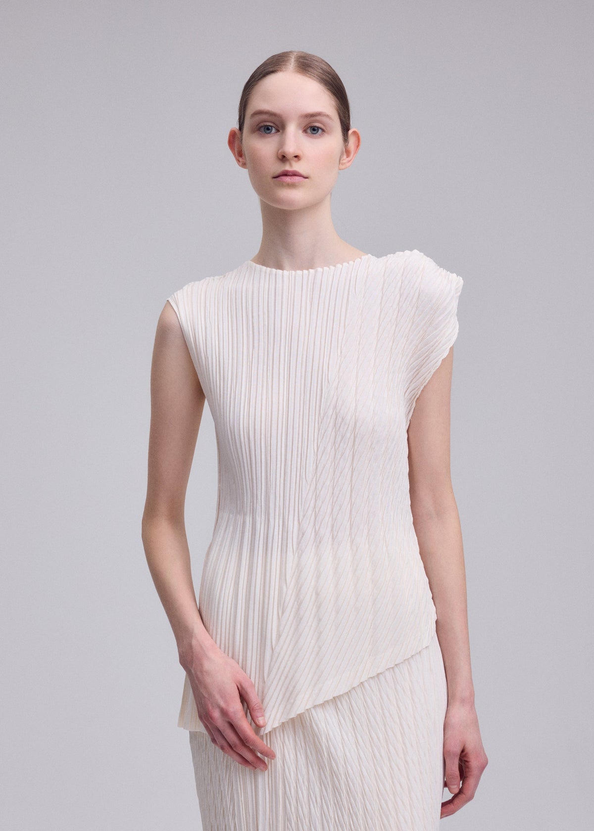 A model wears the ISSEY MIYAKE UNFURLING PLEATS unfurling-pleats-shirt-off-white.