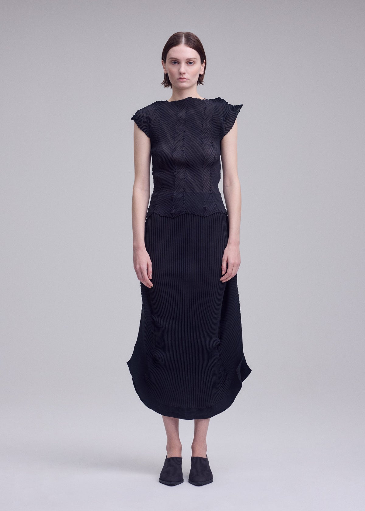 A model wears the ISSEY MIYAKE ZIGZAG PLEATS zigzag-pleats-shirt-black.