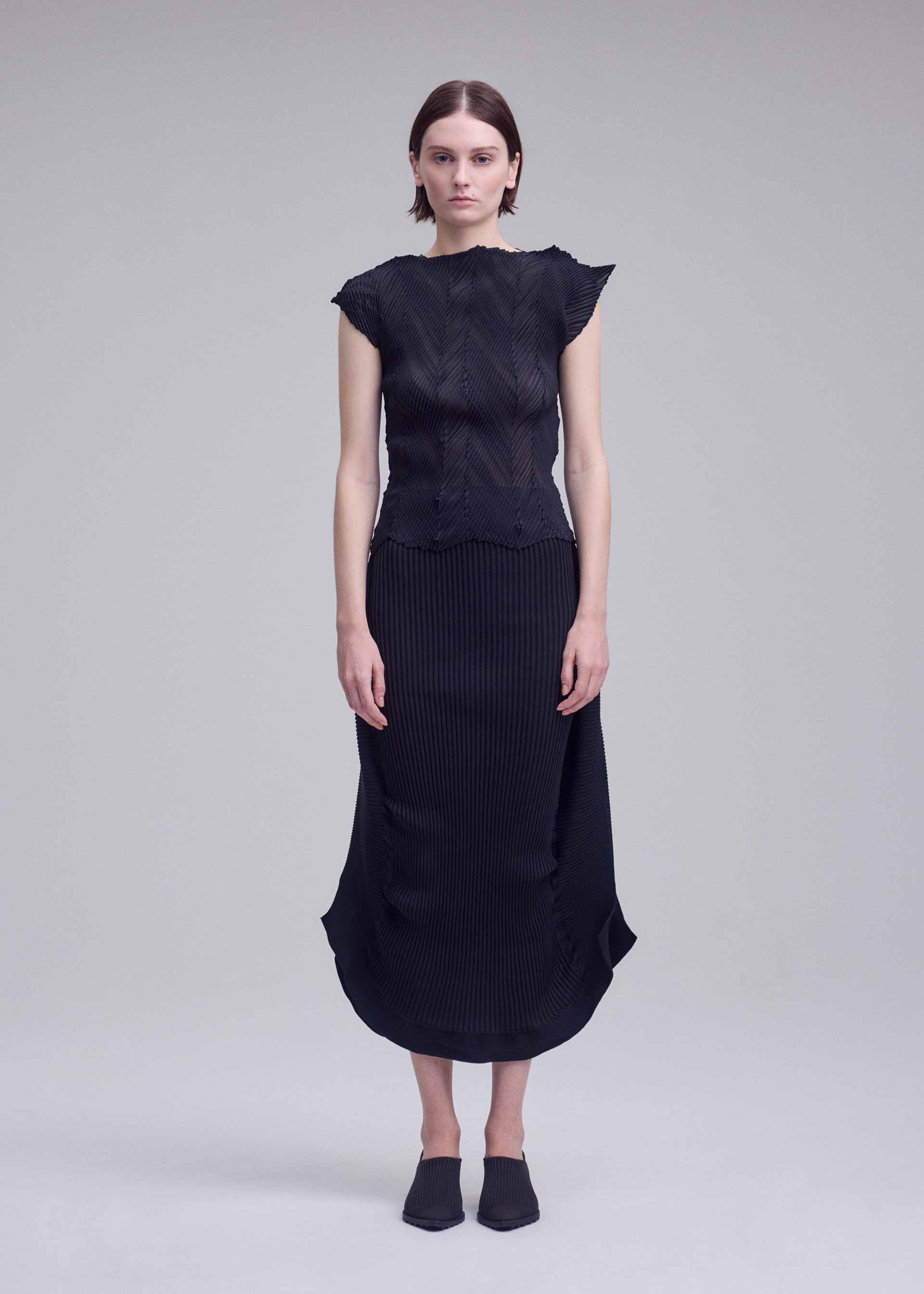 A model wears the ISSEY MIYAKE ZIGZAG PLEATS zigzag-pleats-shirt-black.