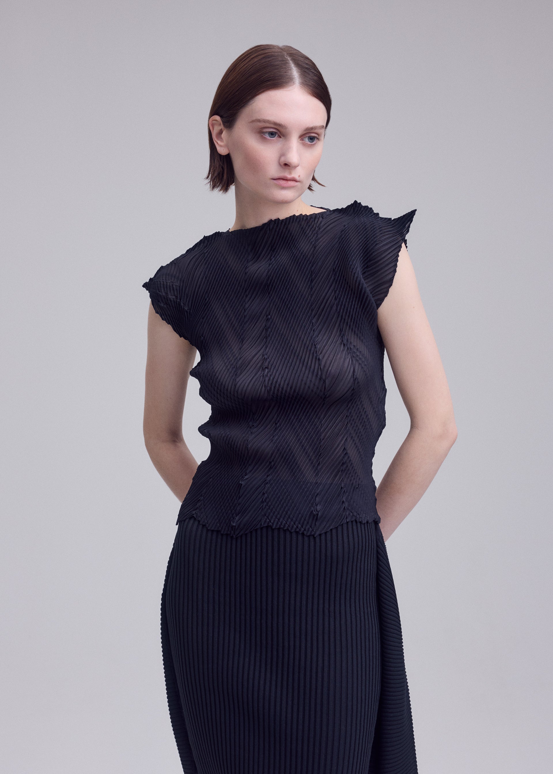 A model wears the ISSEY MIYAKE ZIGZAG PLEATS zigzag-pleats-shirt-black.