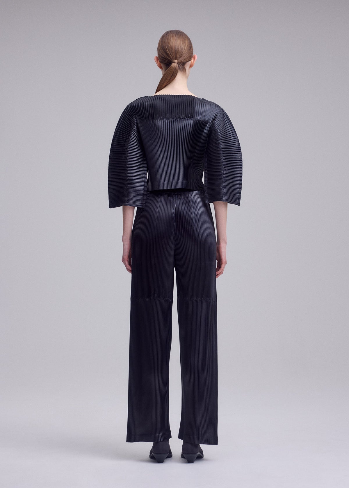 A model wears the ISSEY MIYAKE GLOSSED PANELS PLEATS shirt.