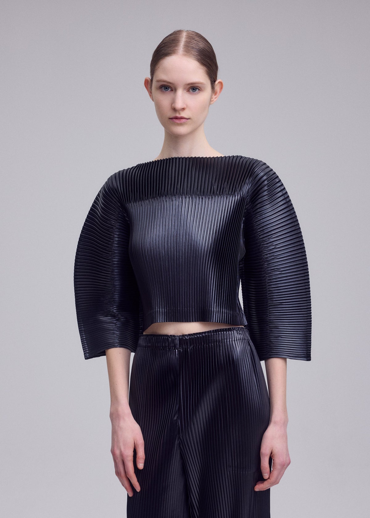 A model wears the ISSEY MIYAKE GLOSSED PANELS PLEATS shirt.