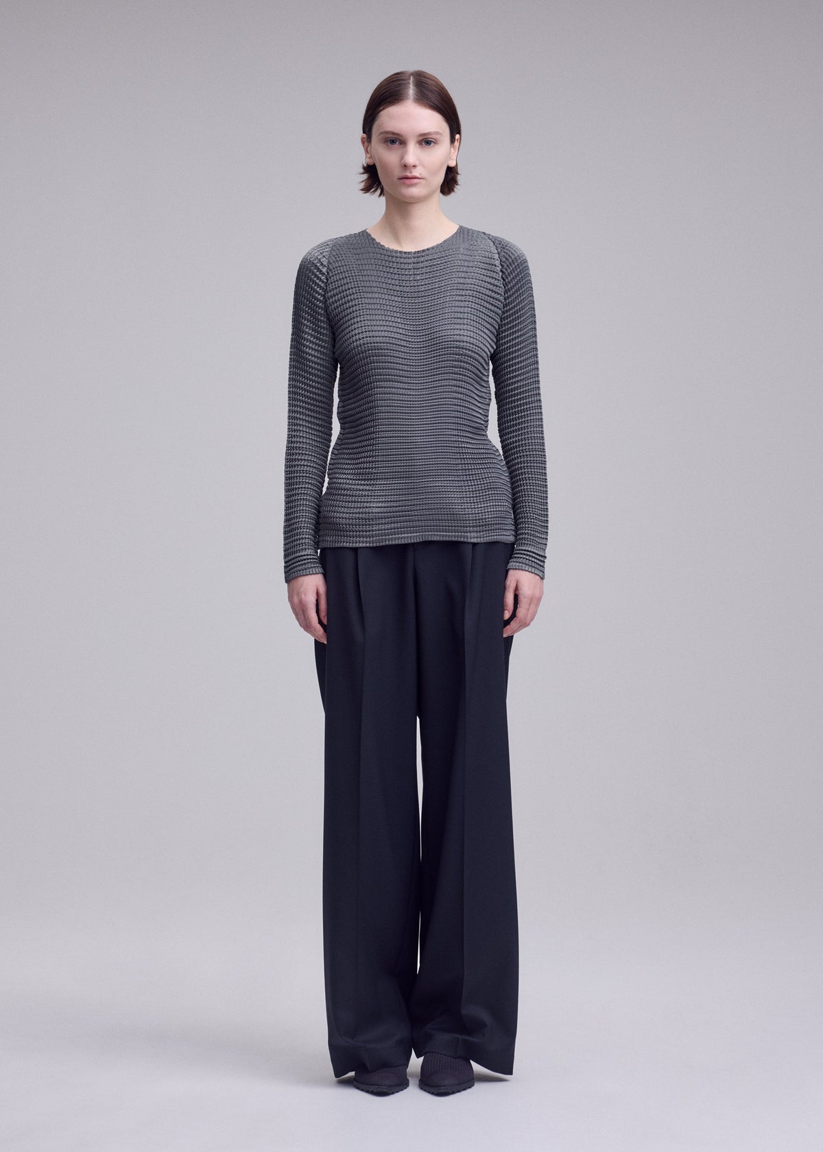 A model wears the ISSEY MIYAKE SUEDE LIKE PLEATS suede-like-pleats-shirt-grey.