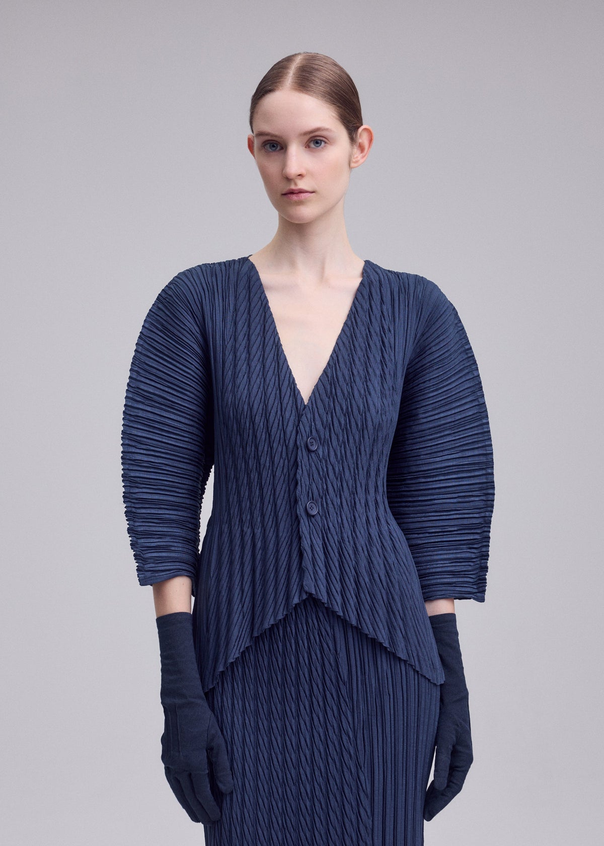 A model wears the ISSEY MIYAKE UNFURLING PLEATS unfurling-pleats-cardigan-green-1.