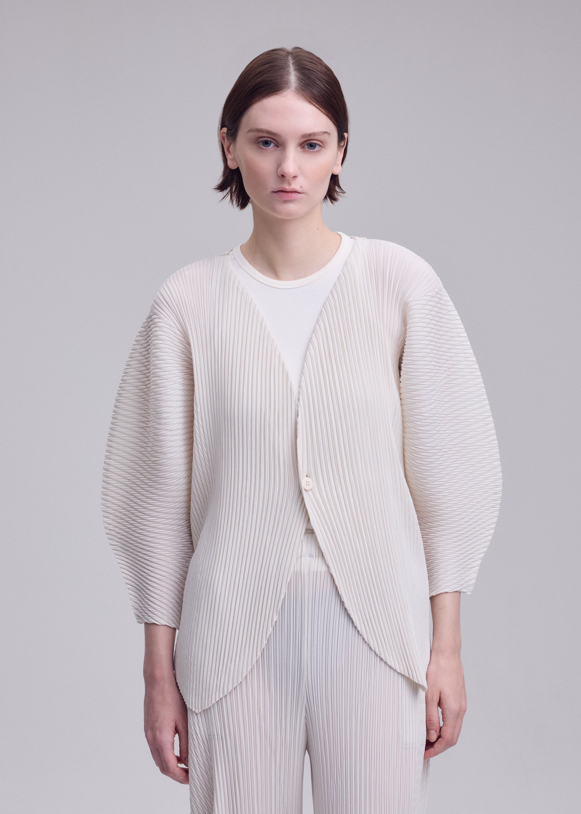 A model wears the ISSEY MIYAKE LEAF PLEATS leaf-pleats-cardigan-off-white.