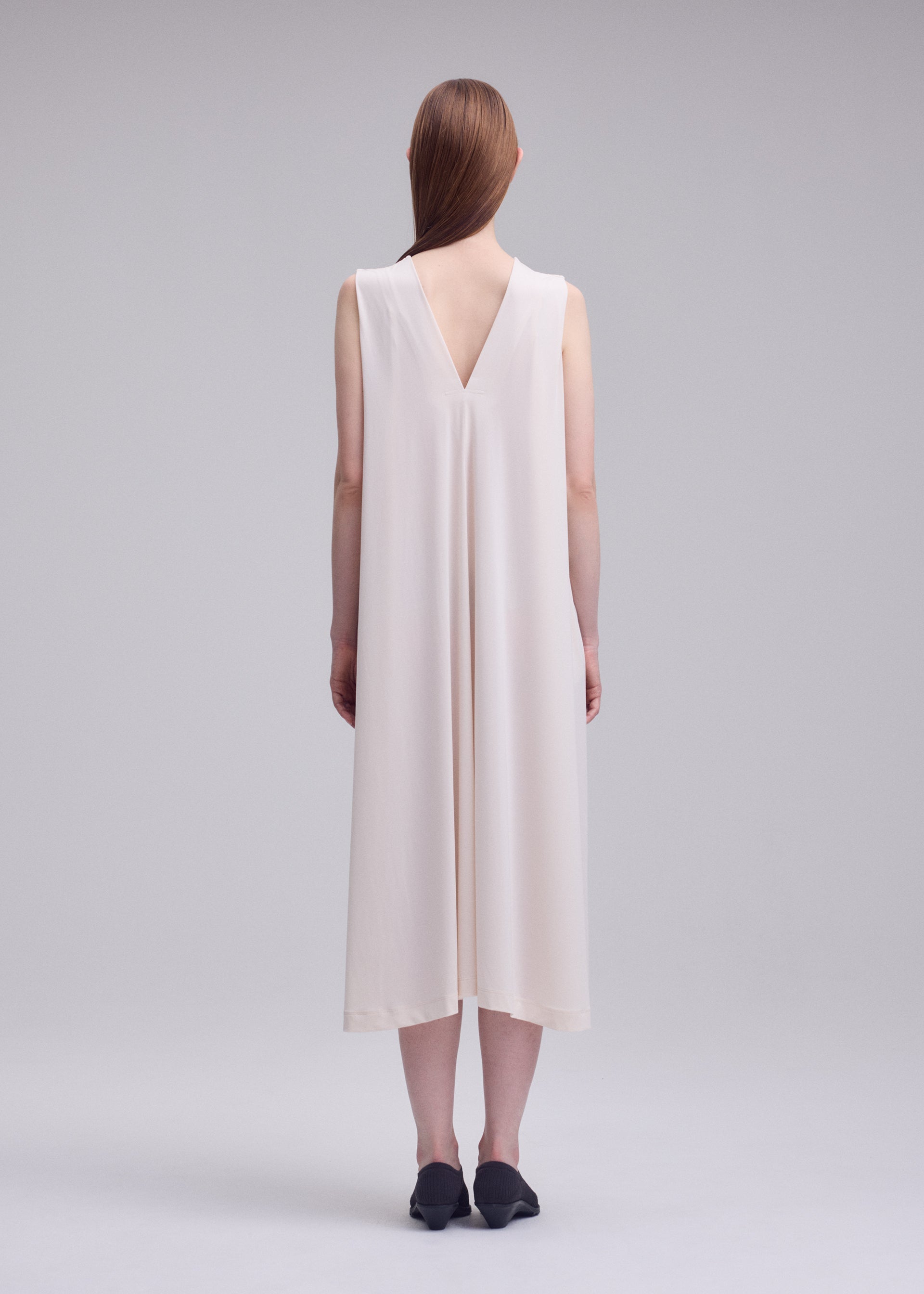 A model wears the ISSEY MIYAKE DRAPE JERSEY-68 drape-jersey-68-dress-off-white.