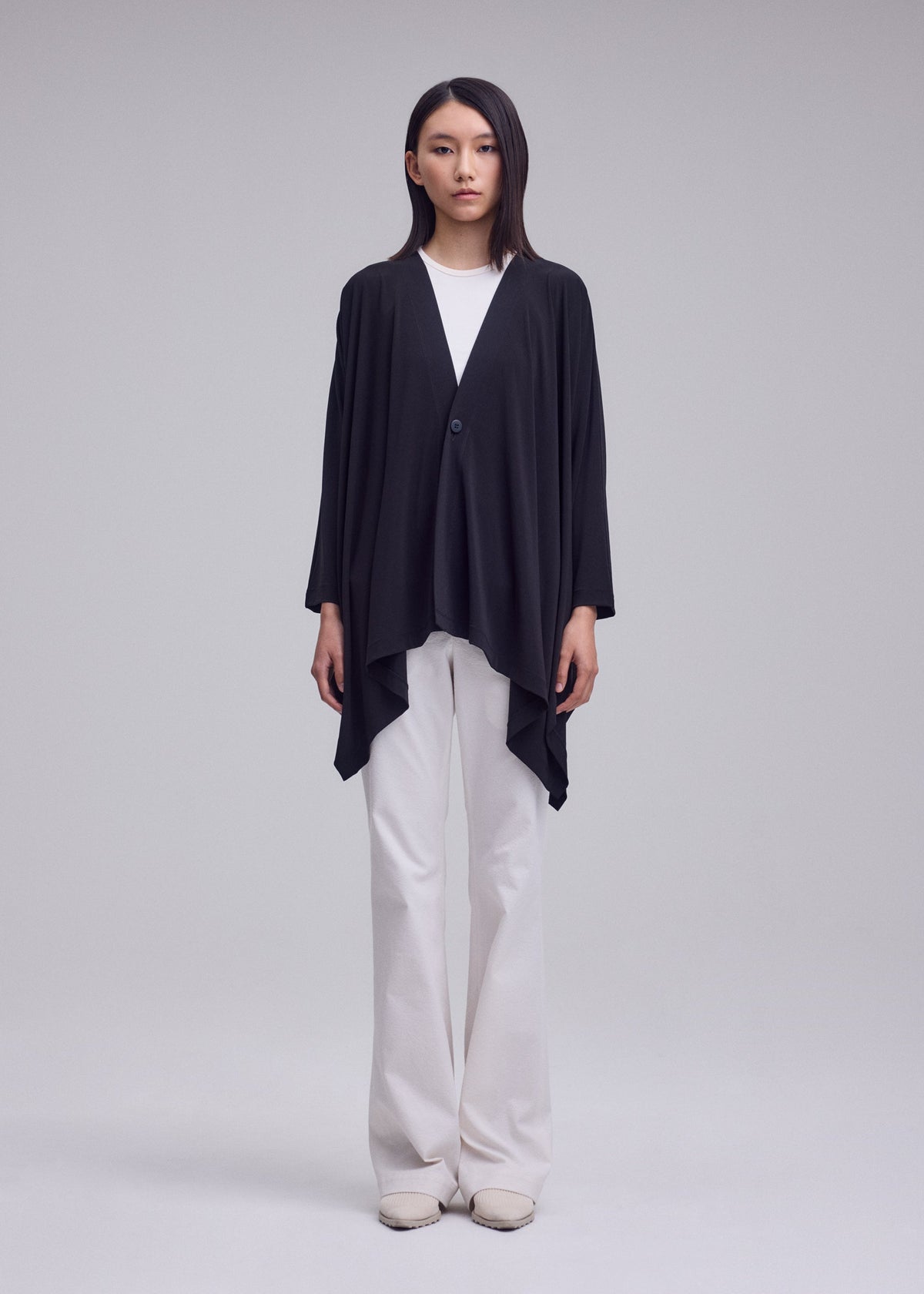 A model wears the ISSEY MIYAKE DRAPE JERSEY-68 drape-jersey-68-cardigan-black-1.