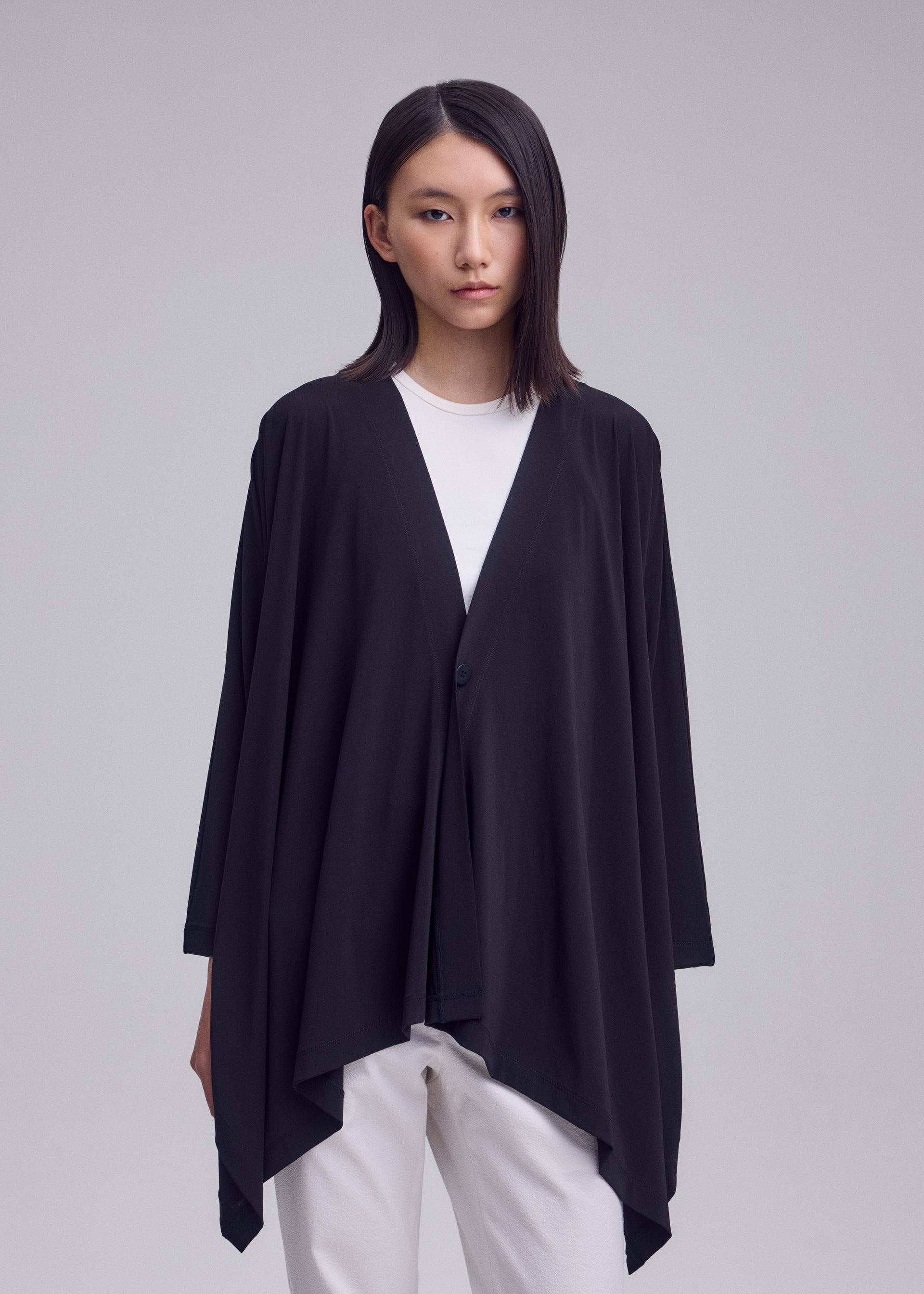 A model wears the ISSEY MIYAKE DRAPE JERSEY-68 drape-jersey-68-cardigan-off-white.