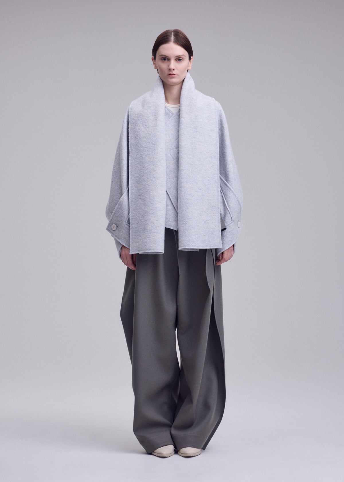 A model wears the ISSEY MIYAKE WOOLEN GRANITE woolen-granite-coat-beige.