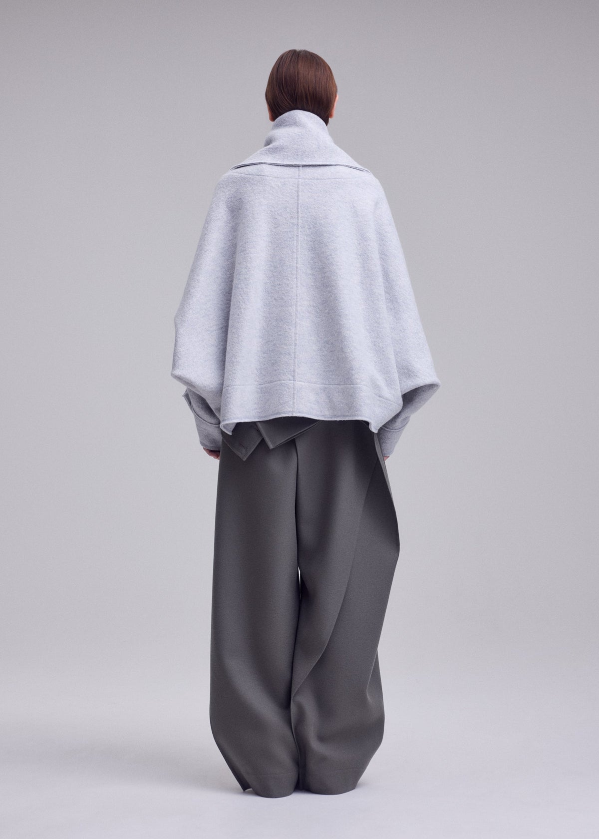 A model wears the ISSEY MIYAKE WOOLEN GRANITE coat.