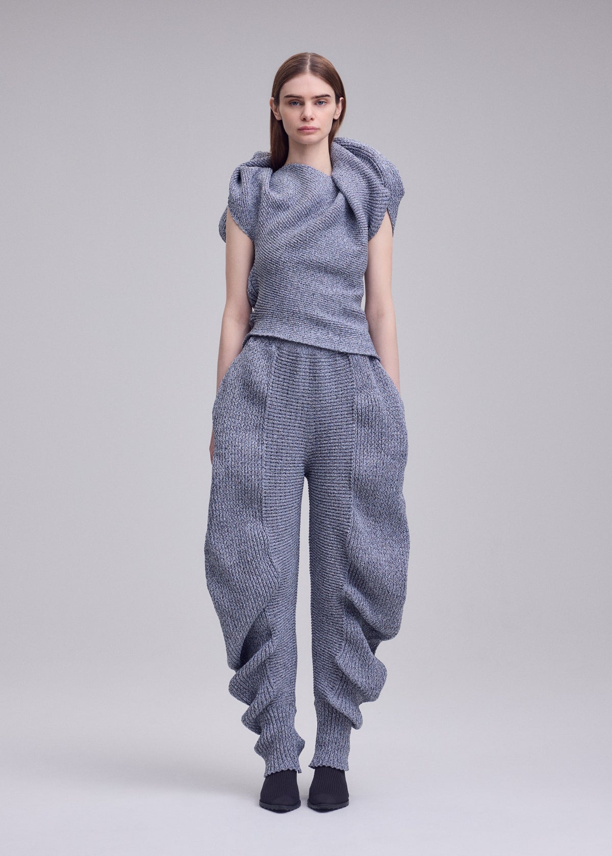 A model wears the ISSEY MIYAKE FOUND STONE found-stone-trousers-black.