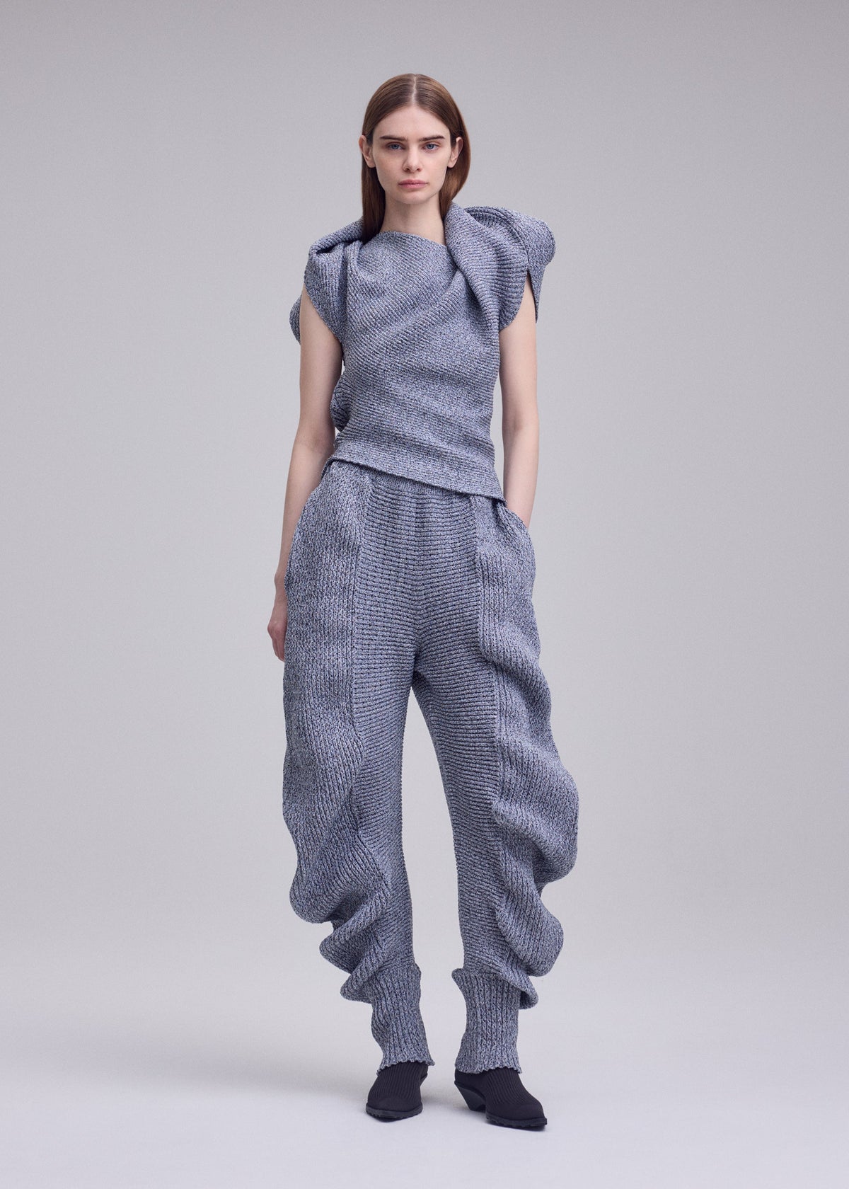A model wears the ISSEY MIYAKE FOUND STONE found-stone-trousers-black.