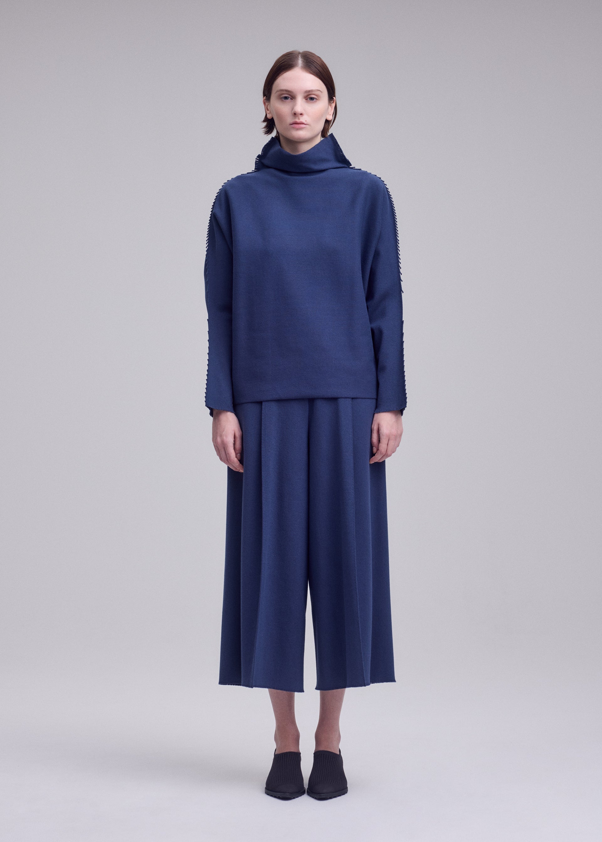 A model wears the ISSEY MIYAKE CAMPAGNE campagne-top-black-10.