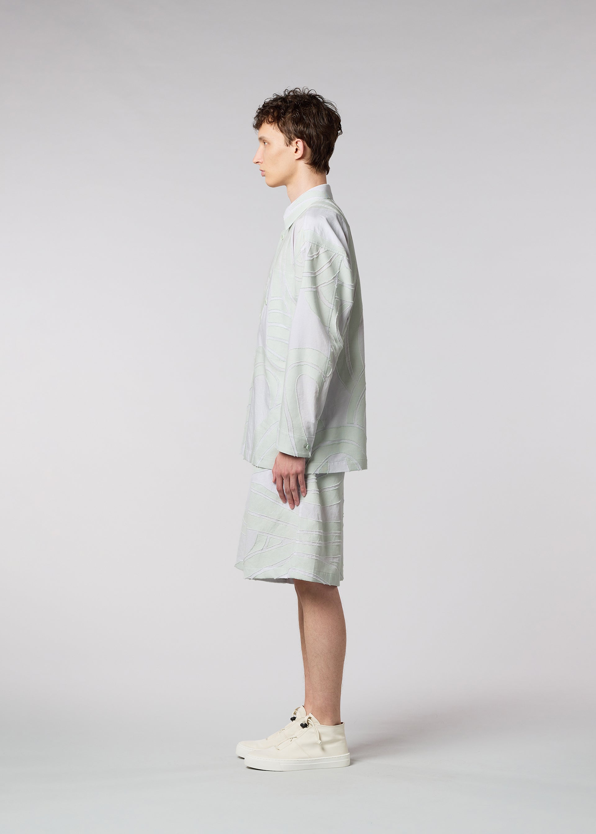 A model wears the ISSEY MIYAKE MEN SCENES shirt.