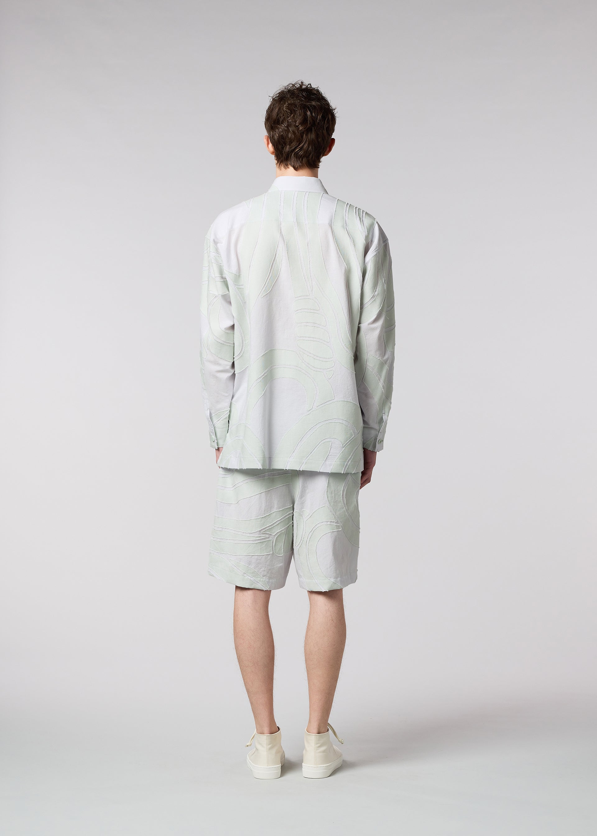 A model wears the ISSEY MIYAKE MEN SCENES shirt.