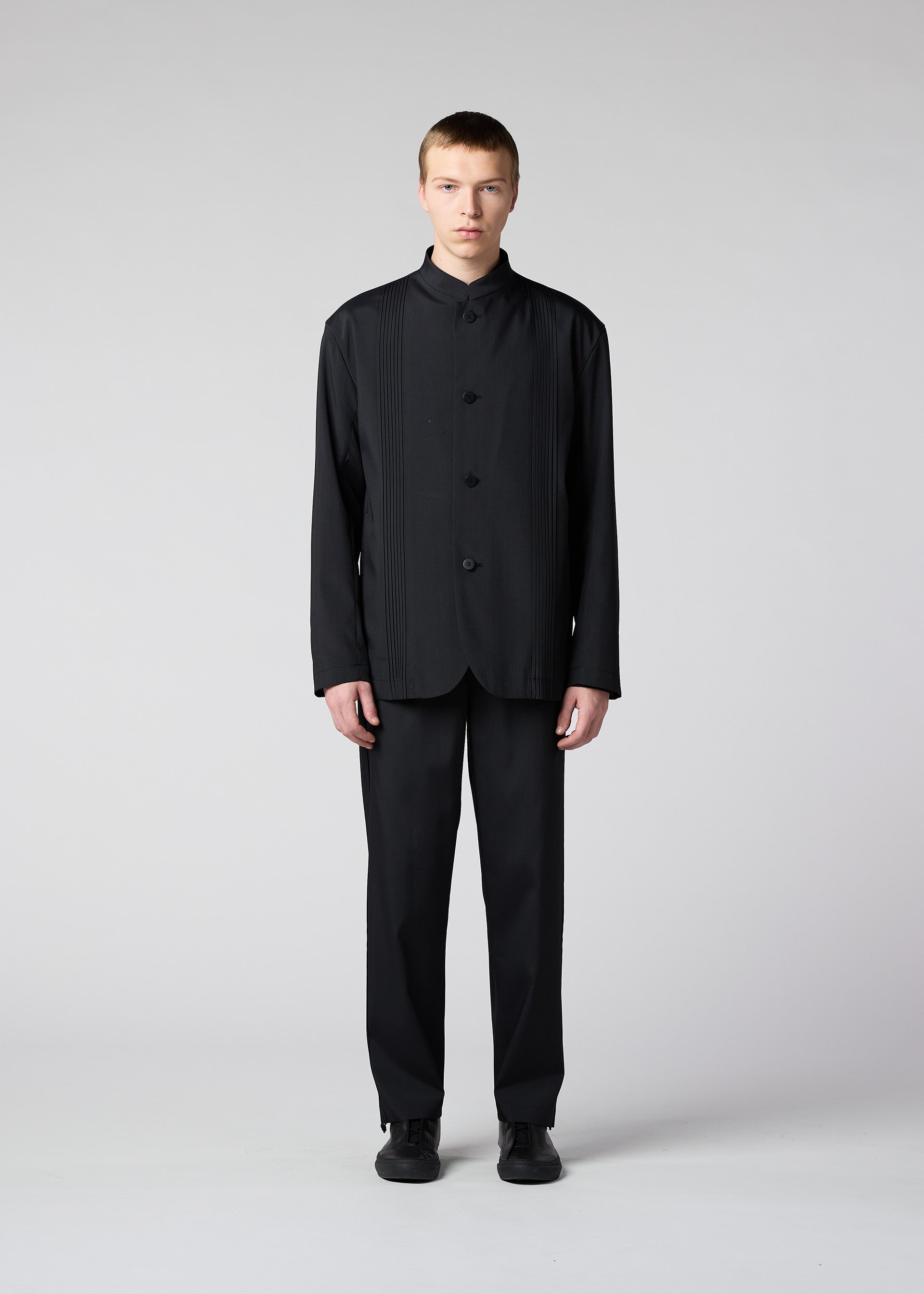 A model wears the IM Men AIR PLEATS trousers.