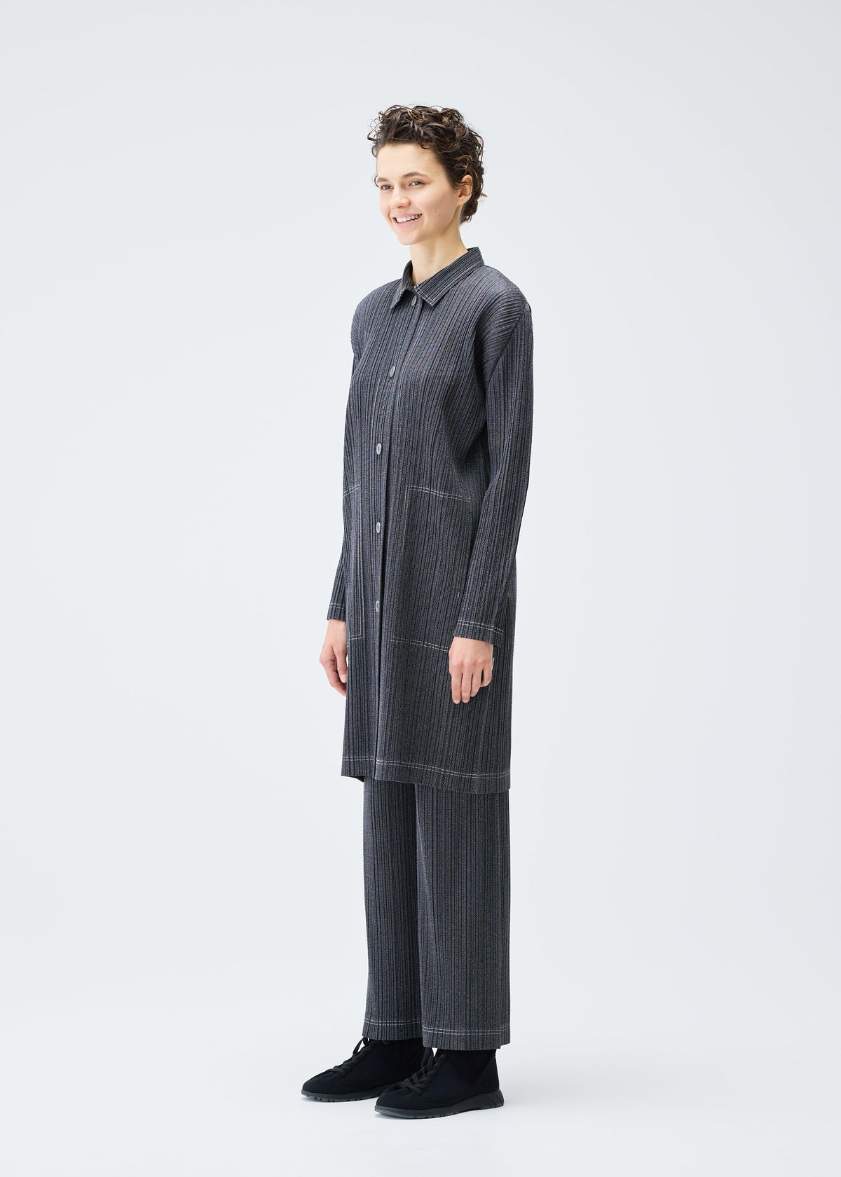 A model wears the PLEATS PLEASE ISSEY MIYAKE COTTON DENIM coat.