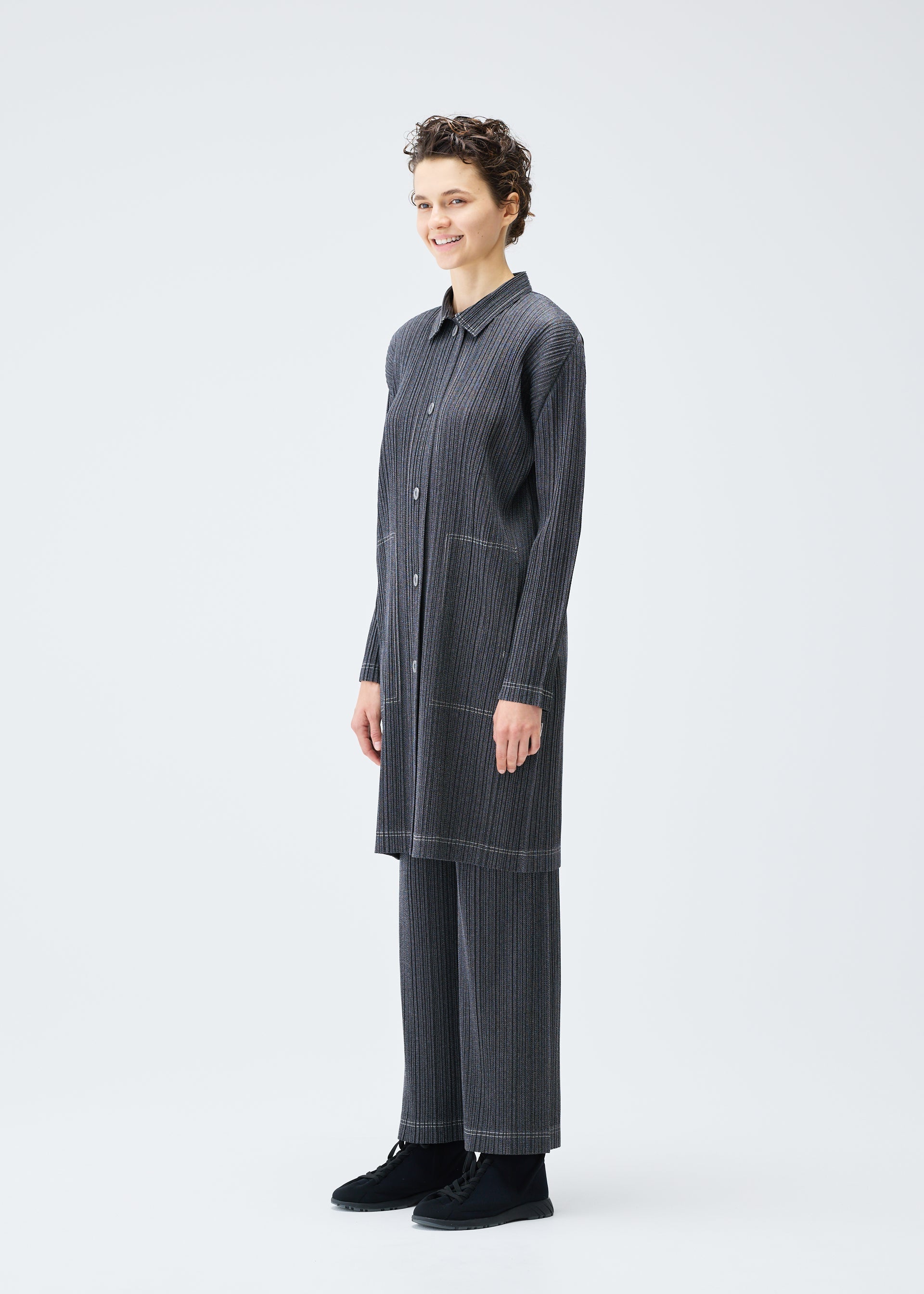 A model wears the PLEATS PLEASE ISSEY MIYAKE COTTON DENIM coat.