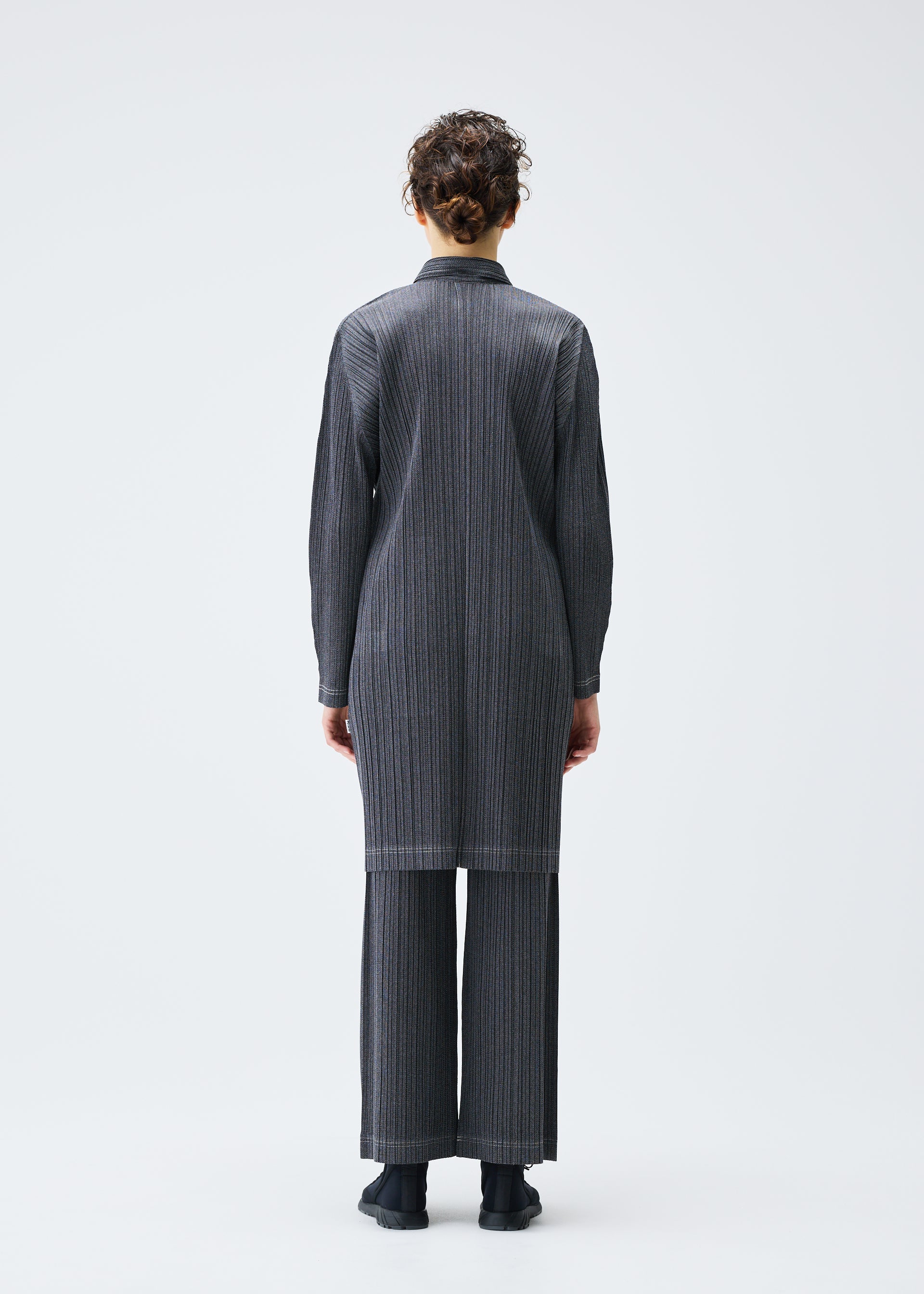 A model wears the PLEATS PLEASE ISSEY MIYAKE COTTON DENIM coat.