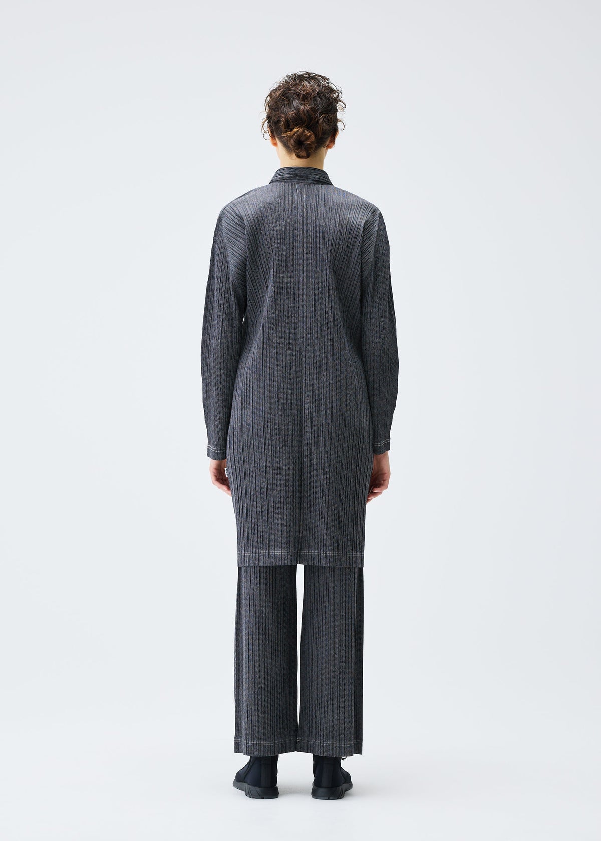 A model wears the PLEATS PLEASE ISSEY MIYAKE COTTON DENIM coat.