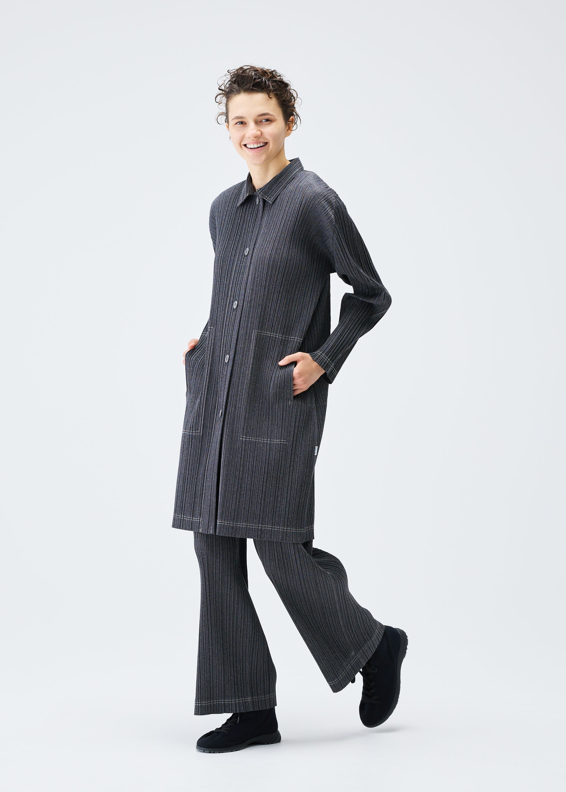 A model wears the PLEATS PLEASE ISSEY MIYAKE COTTON DENIM coat.