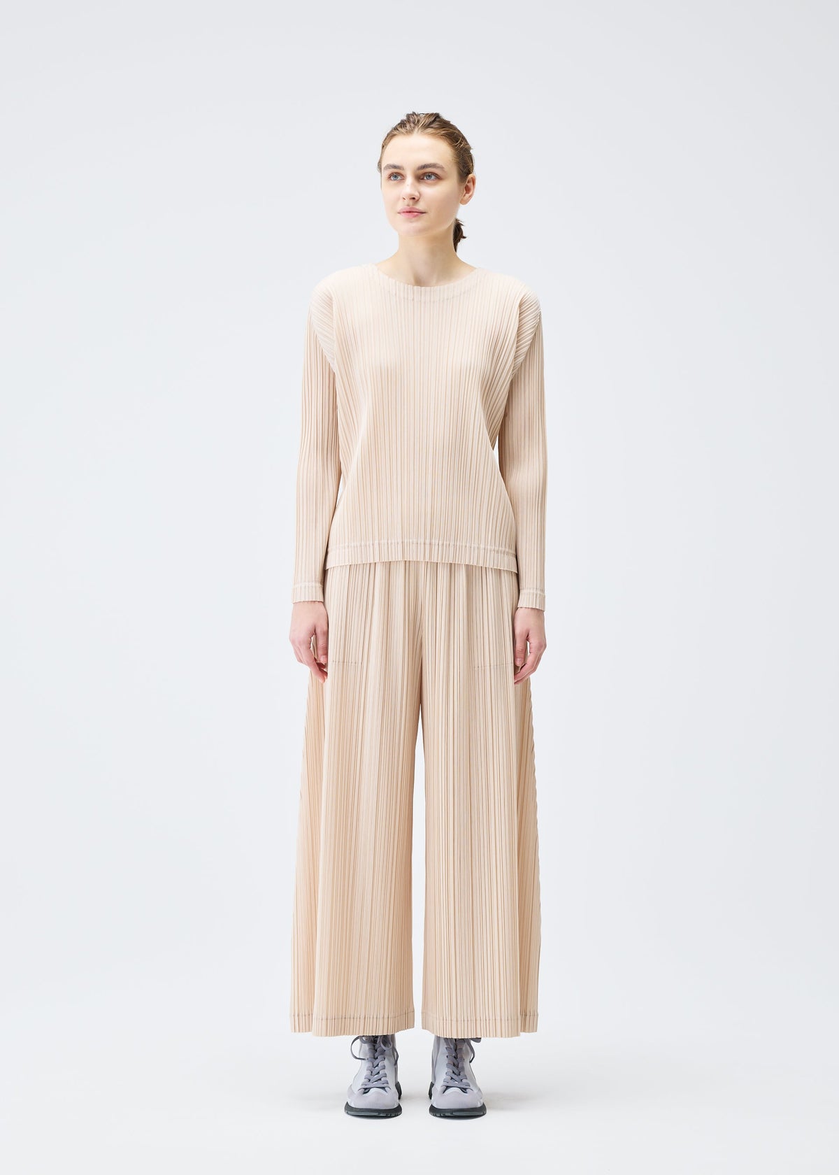 A model wears the Pleats Please Issey Miyake WOOL PLEATS trousers.