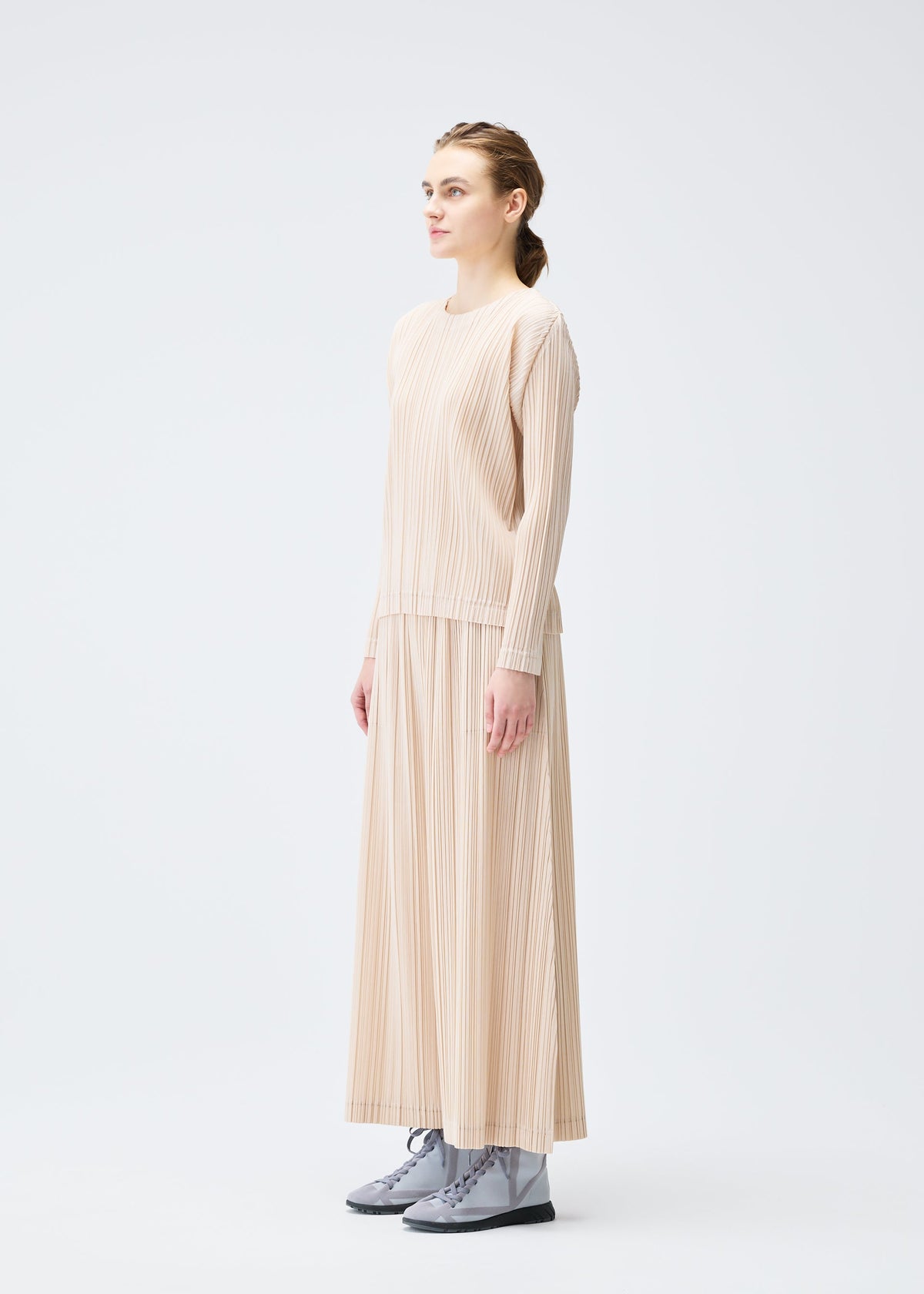 A model wears the Pleats Please Issey Miyake WOOL PLEATS trousers.