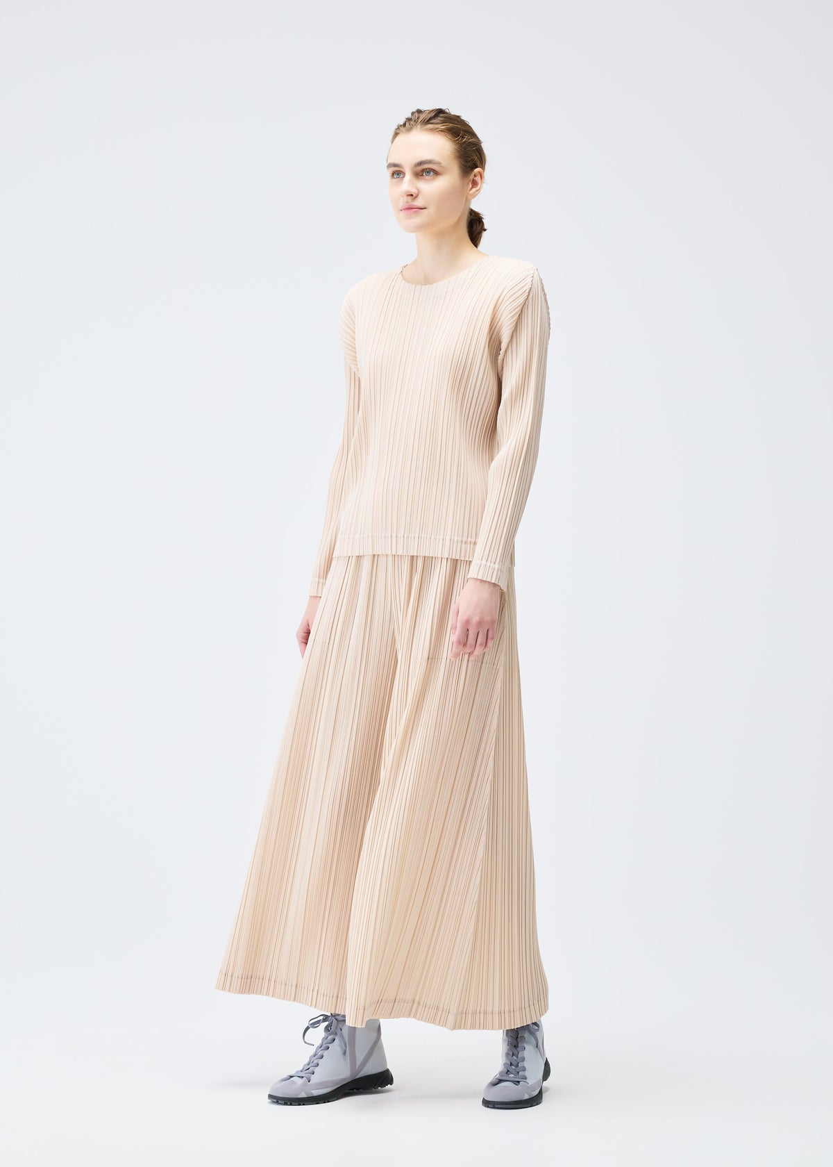 A model wears the Pleats Please Issey Miyake WOOL PLEATS trousers.