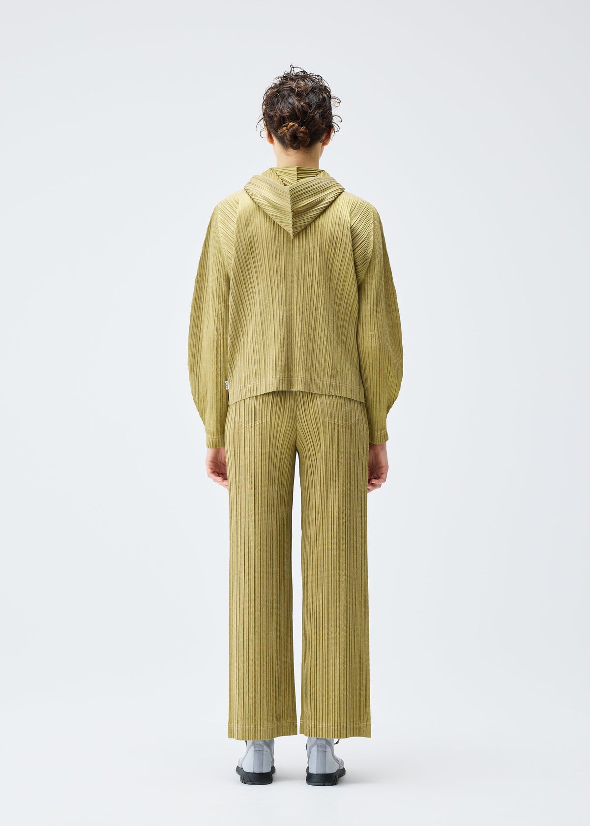 A model wears the PLEATS PLEASE ISSEY MIYAKE COTTON DENIM trousers.
